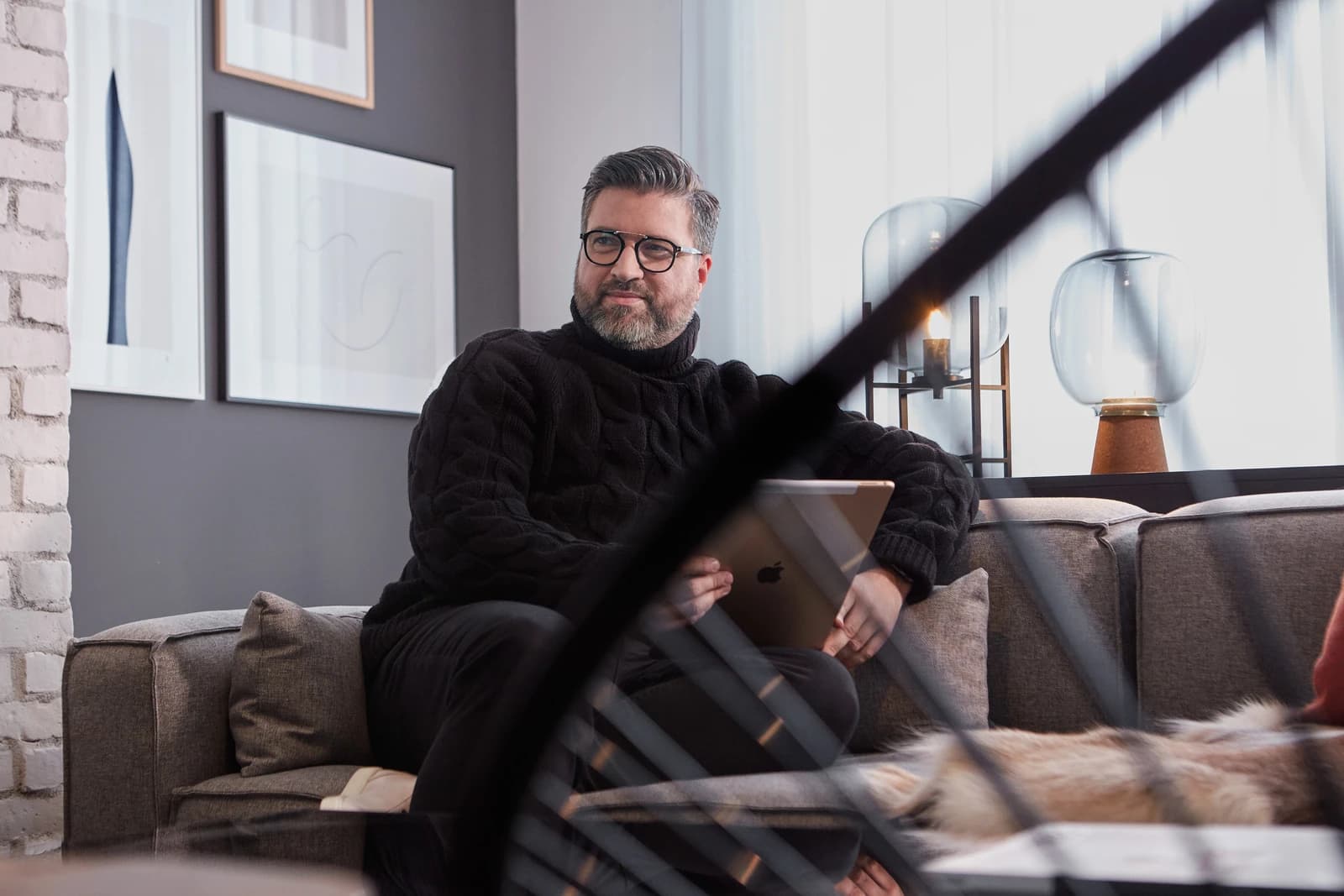 Dominic De Freitas, Principal at Figure3 Interior Design, sitting on a couch holding a tablet.