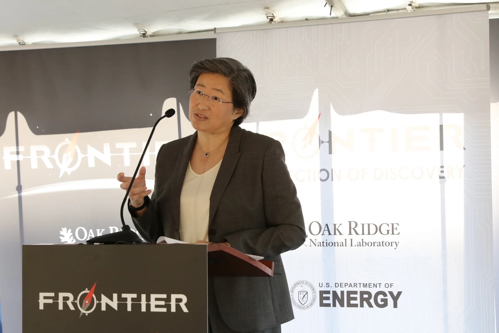 Lisa Su, CEO of AMD, speaking at a podium with a microphone at an event.