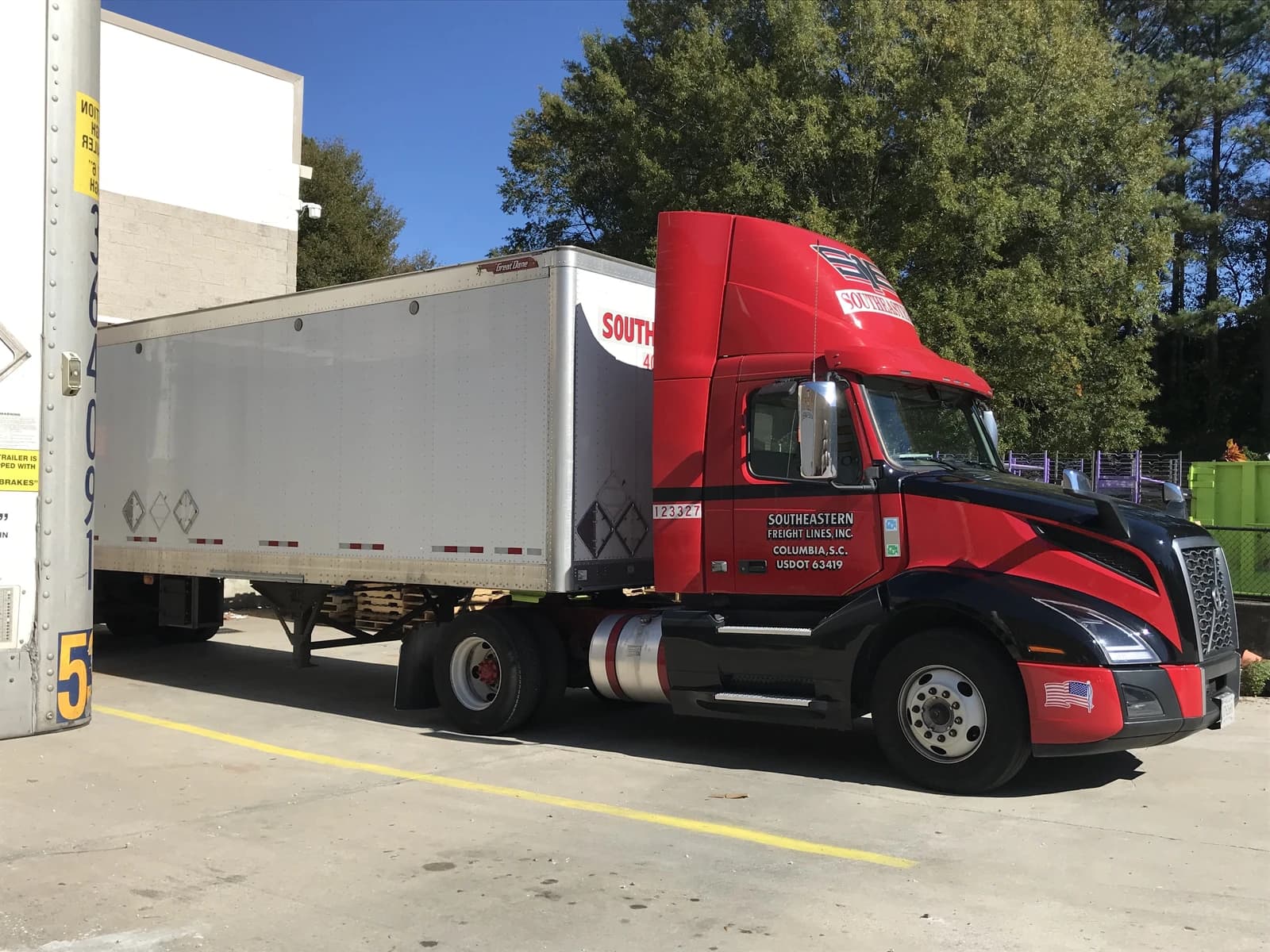 A Southeastern Freight Lines truck and trailer parked outside during the day.