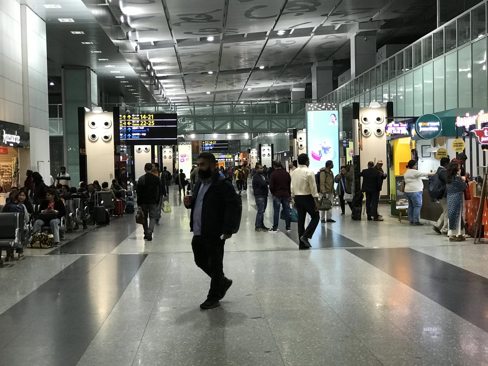 Travelers walk through Netaji Subhas Chandra Bose International Airport concourse.