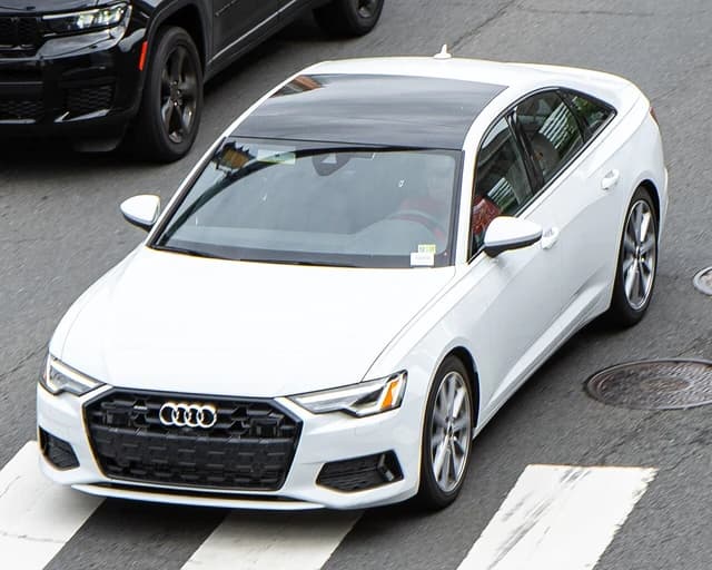 White Audi A6 (C8) sedan driving on a city street.
