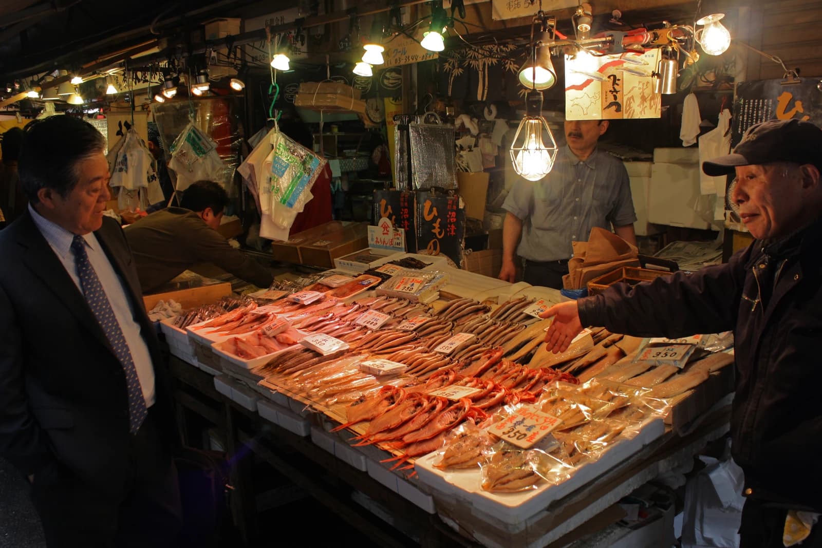 Men looking at various types of fresh fish displayed on a market stall.