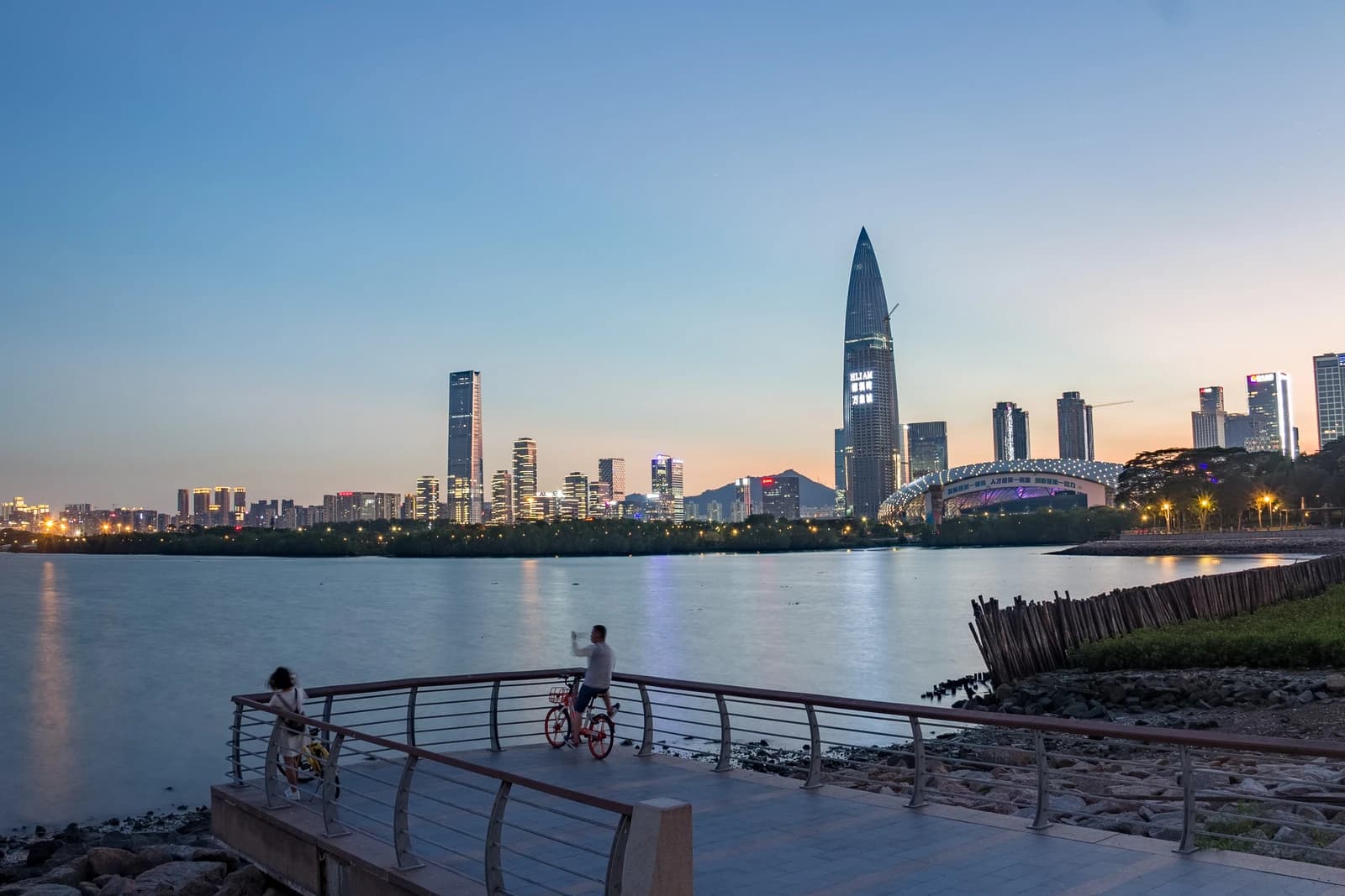 Skyline of Shenzhen, China, featuring modern skyscrapers and a waterfront promenade at dusk.