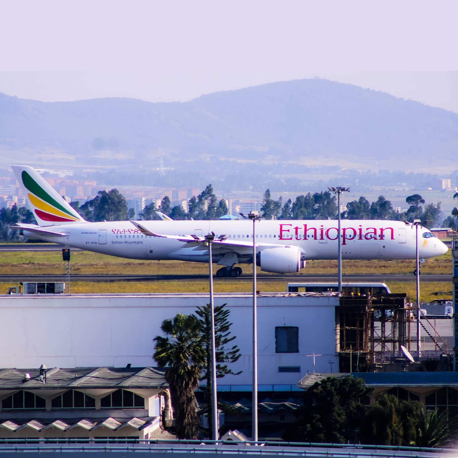 Ethiopian Airlines Airbus A350 aircraft on airport tarmac, mountains in distance.