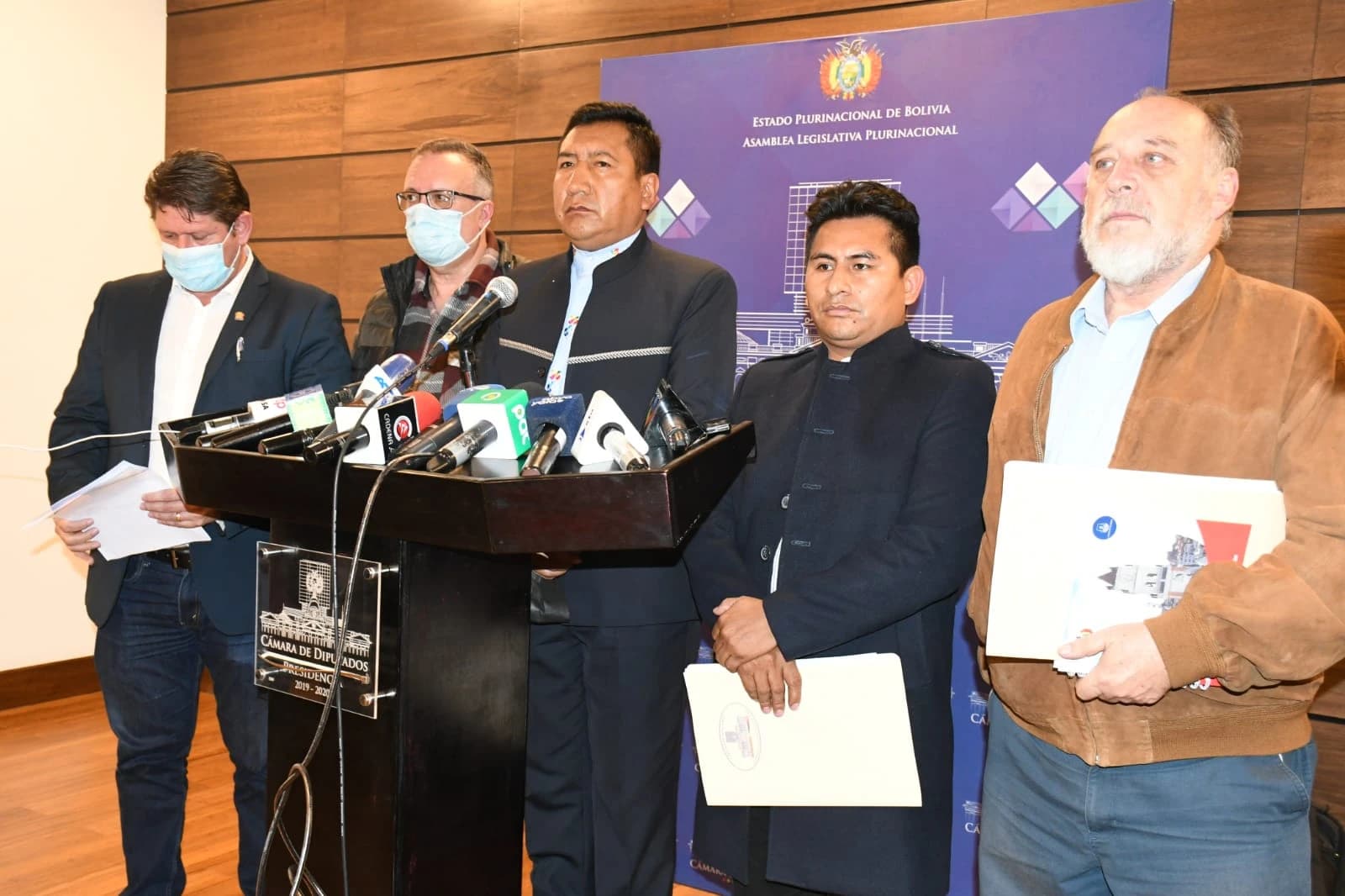 Group of five men standing at podiums during a press conference in La Paz.