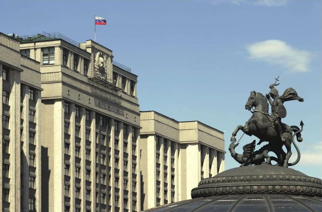 The State Duma building with the Russian national flag flying from the roof, next to a statue of Saint George.