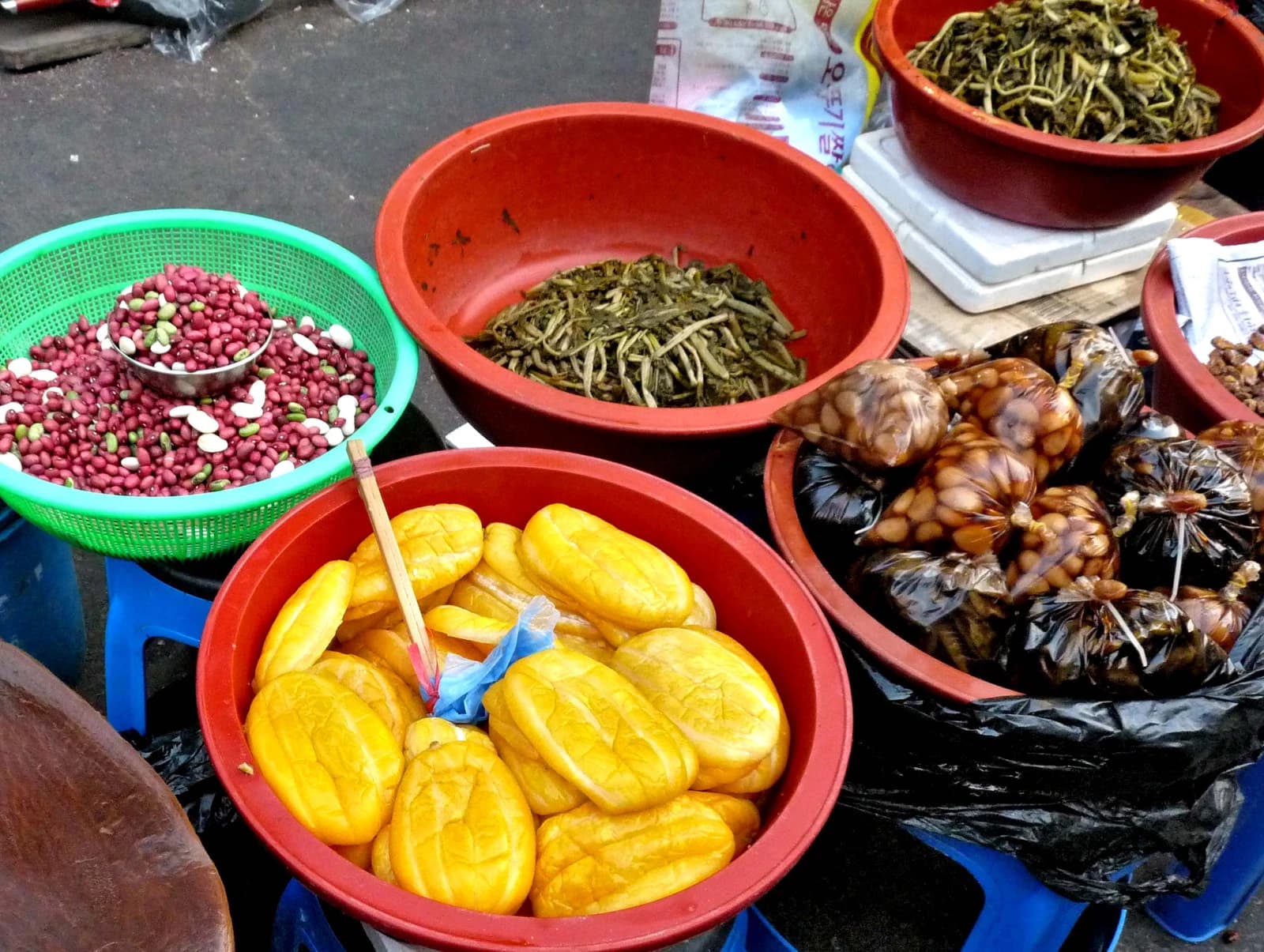 Dishes of Korean food including jangajji, namul, and beans displayed at Namdaemun Market in Seoul.
