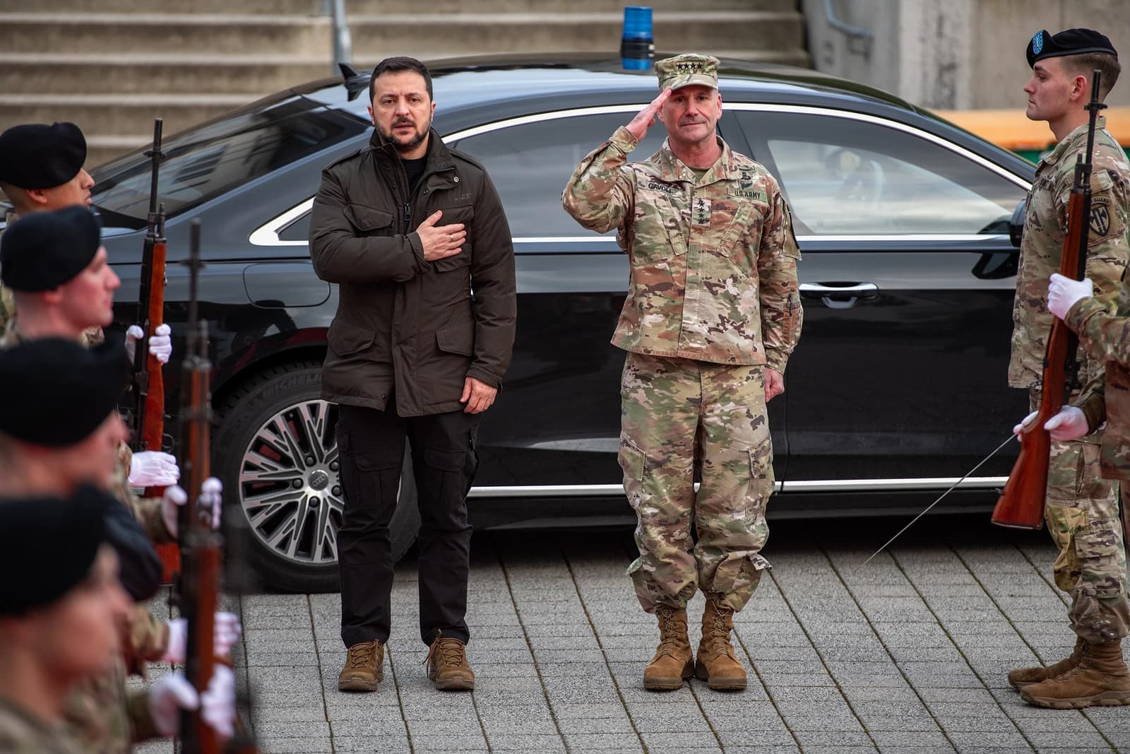General Christopher Cavoli salutes while Ukrainian President Volodymyr Zelenskyy stands with hand over heart.