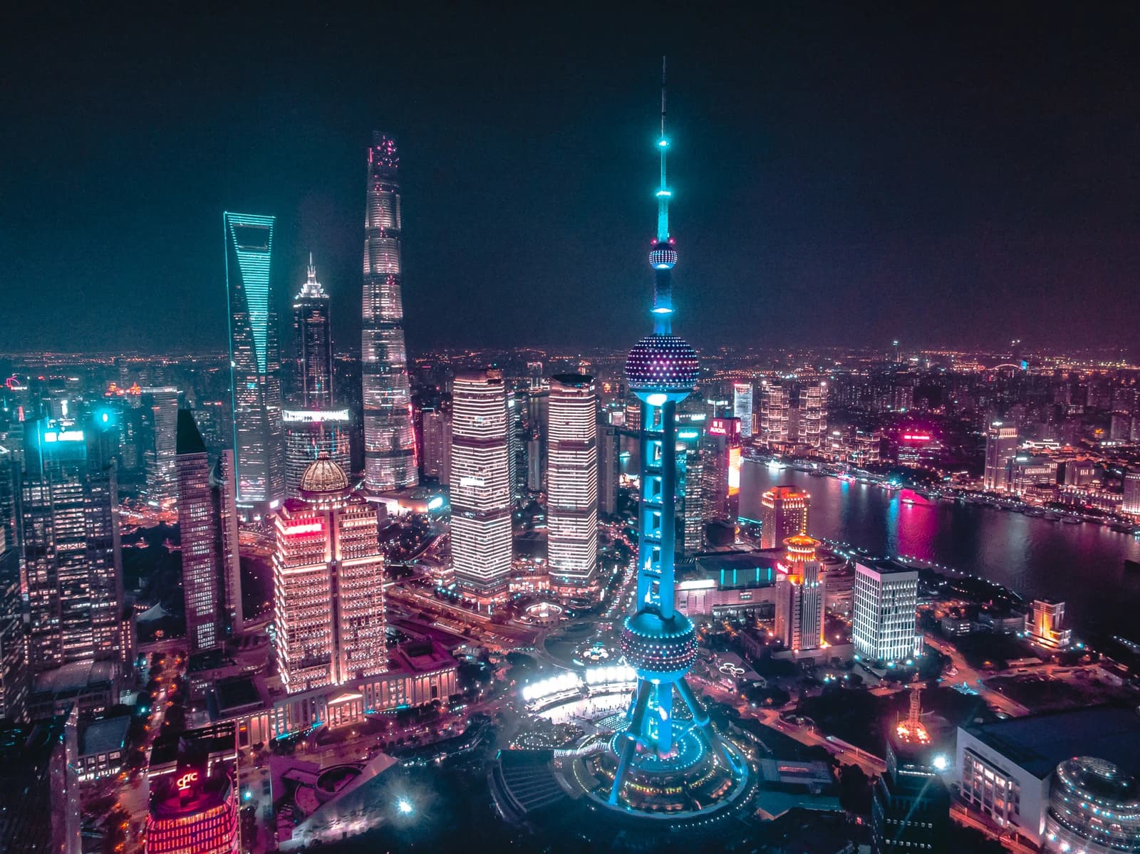 Aerial view of Shanghai's illuminated Pudong skyline and Oriental Pearl TV Tower at night.