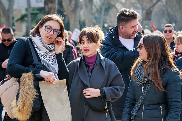People in a crowd outdoors, some individuals engaging in conversation.