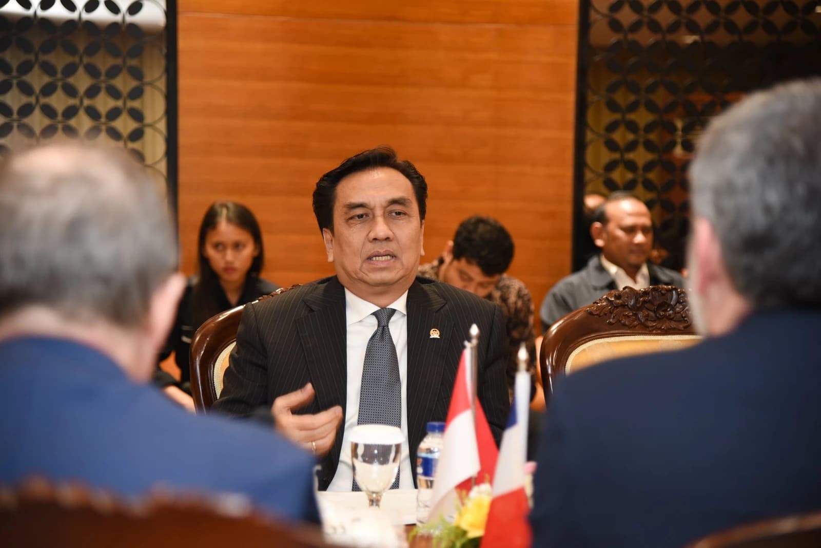 Effendi Simbolon, wearing a suit and tie, seated at a table during a meeting.