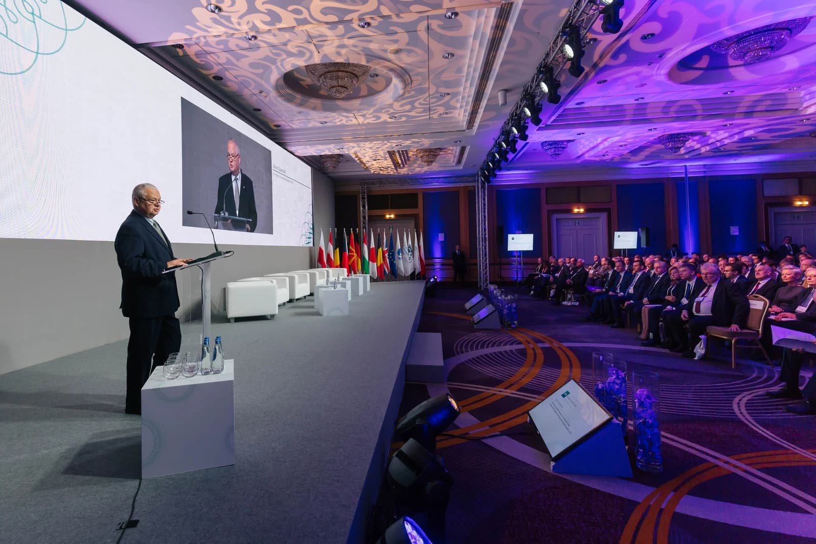 Adam Glapiński, Governor of the National Bank of Poland, speaking at a podium in a conference hall.