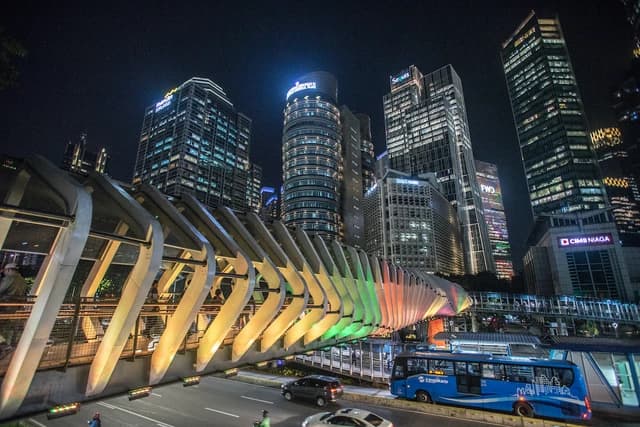 Pedestrian bridge leading to skyscrapers in Jakarta's SCBD business district at night.