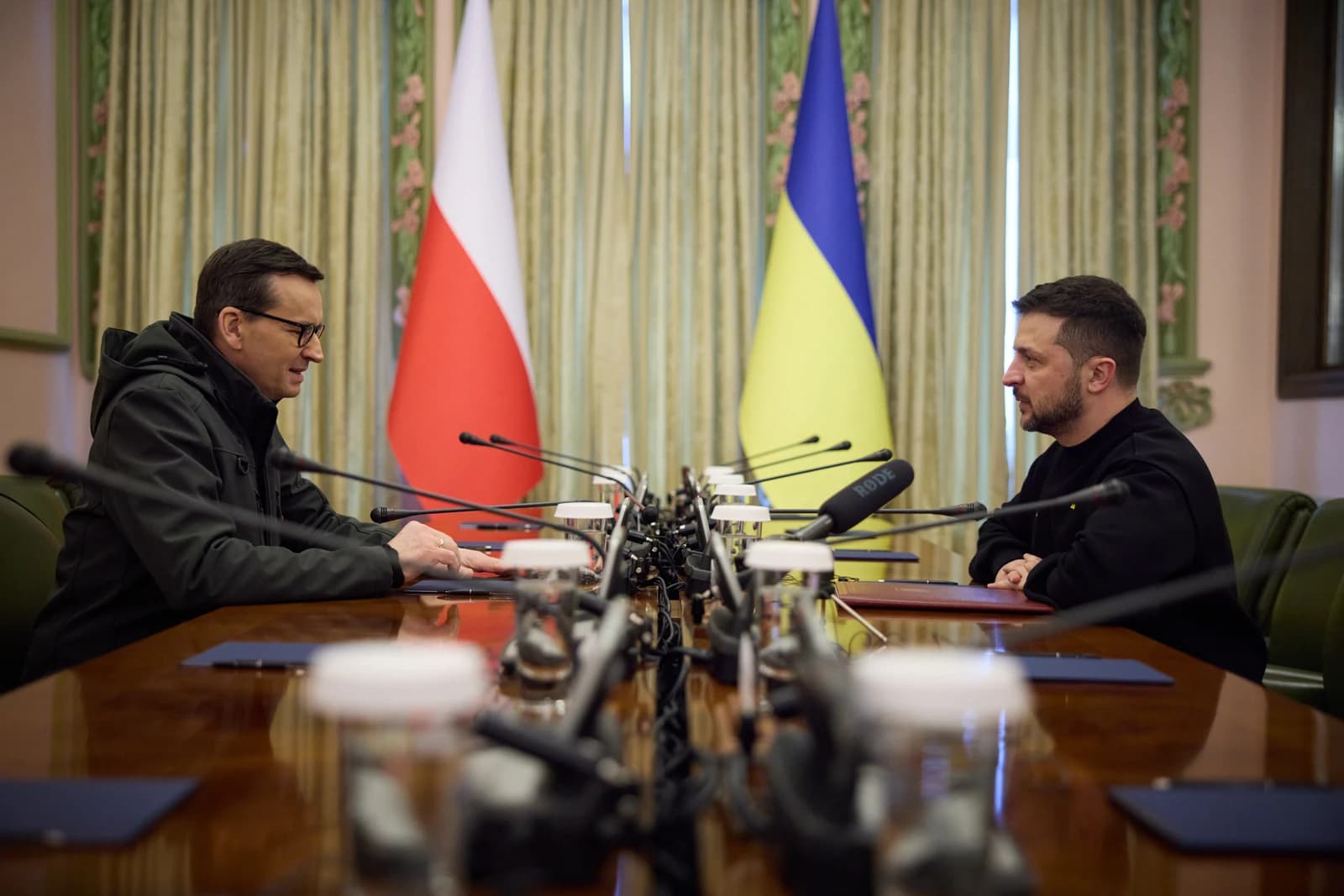 Ukrainian President Volodymyr Zelenskyy meets with Polish Prime Minister Mateusz Morawiecki at a table.