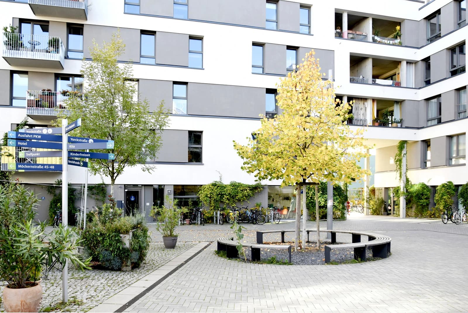 Apartment buildings in Möckernkiez, Berlin, with a directional sign and autumn tree.