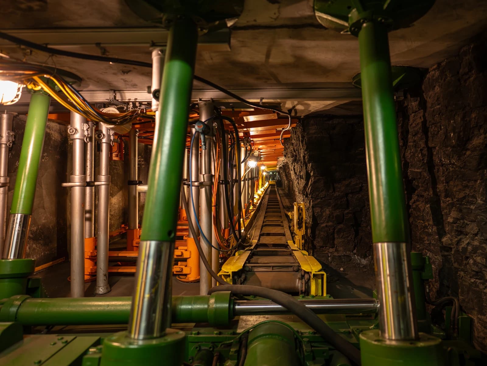 An underground coal mining tunnel featuring mechanical shield support and a rail track.