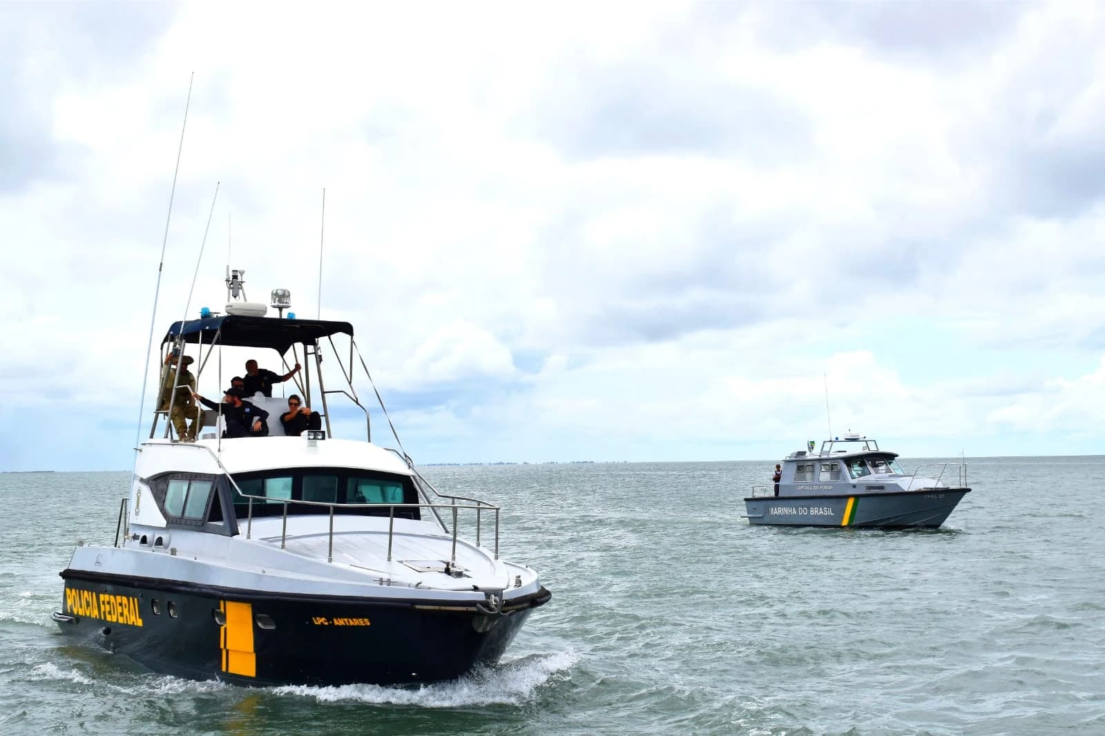 Brazilian Federal Police and Navy personnel on two patrol boats in open water.