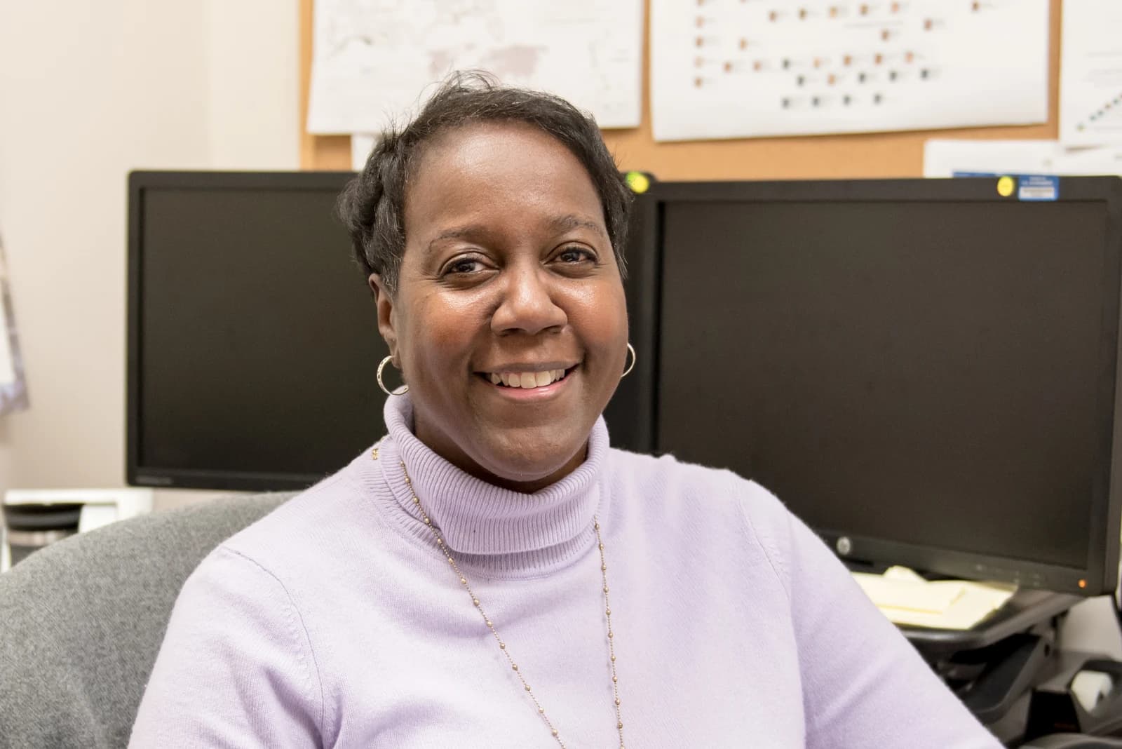 Human Resources Manager smiling, sitting at a desk in an office.