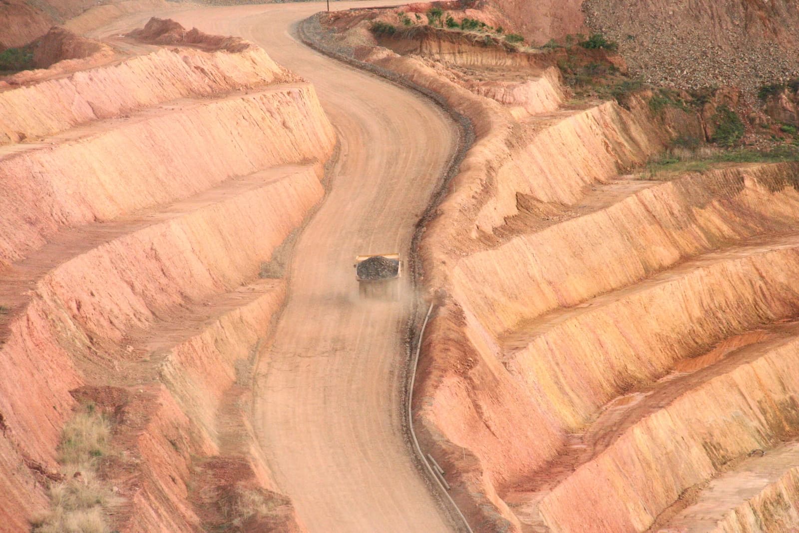 Truck hauling ore through a terraced open-pit mine.