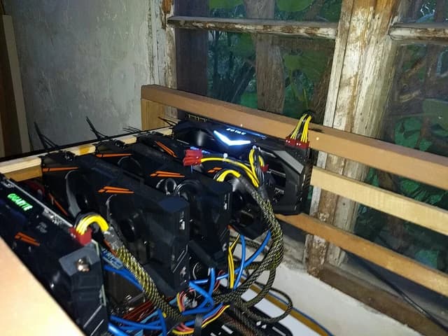 Cryptocurrency mining rig with multiple graphics cards and wiring visible.