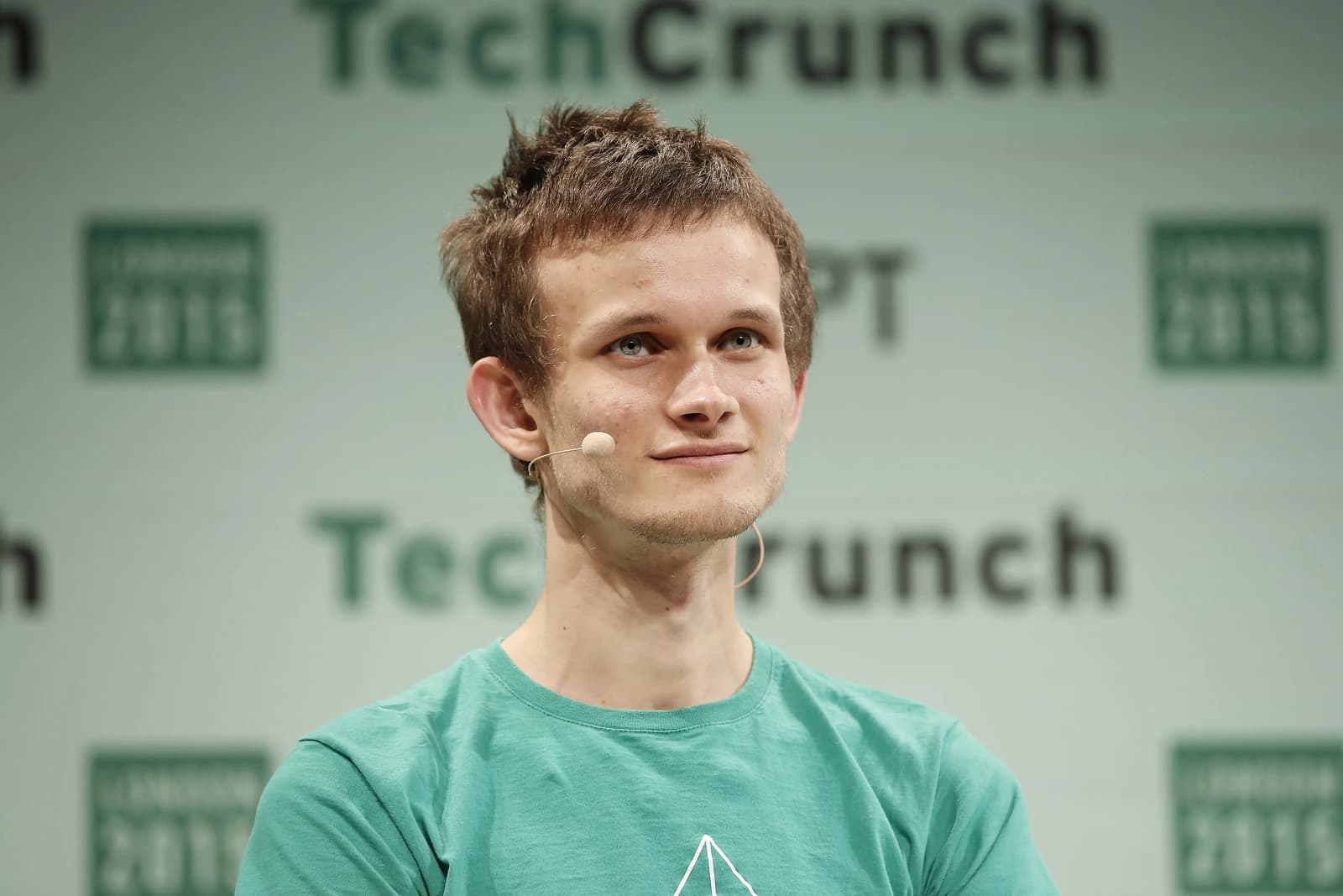 Vitalik Buterin, creator of Ethereum, smiling with a microphone on his cheek.