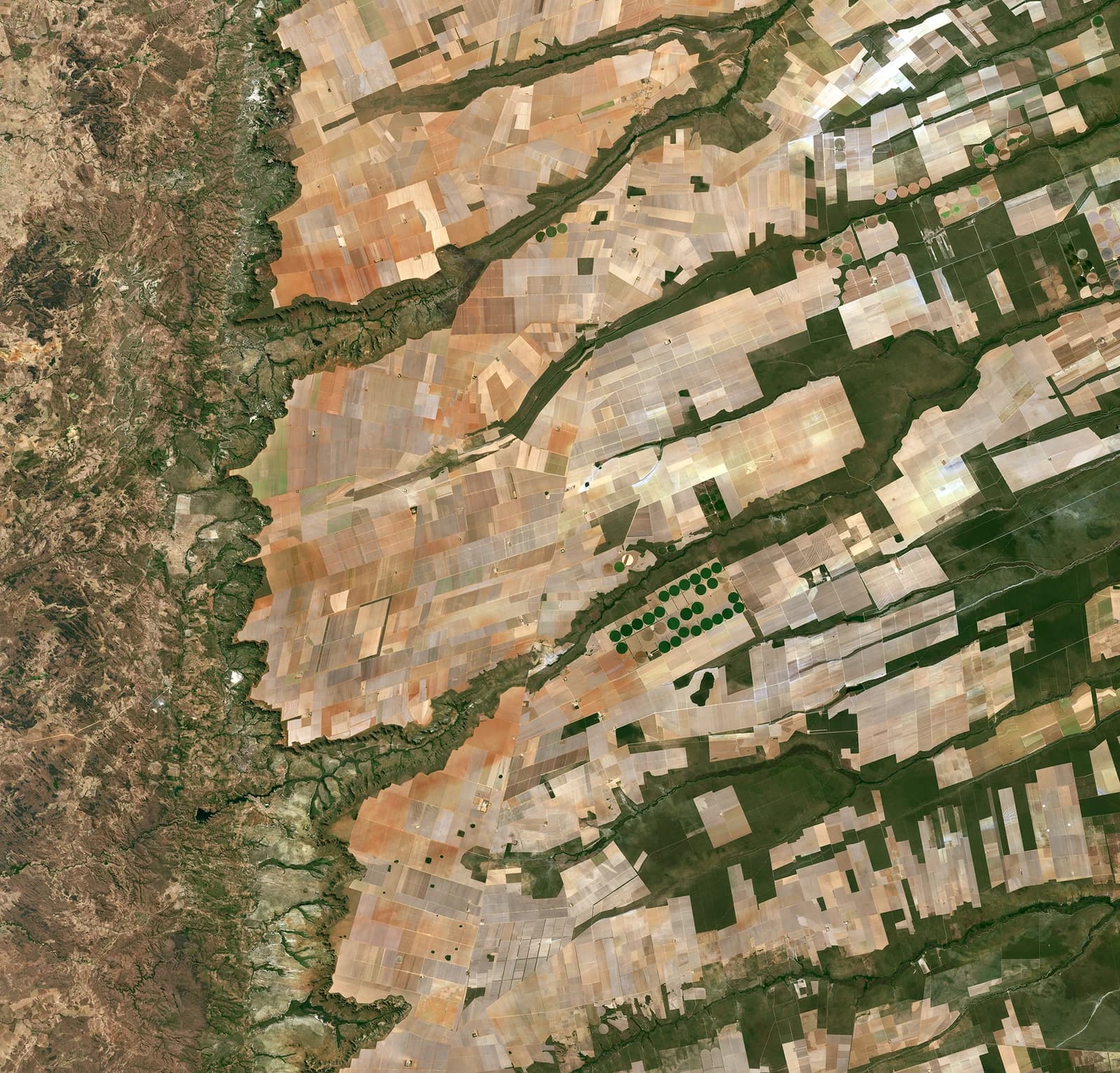 Aerial satellite view showing diverse agricultural fields and natural landscapes in Brazil.