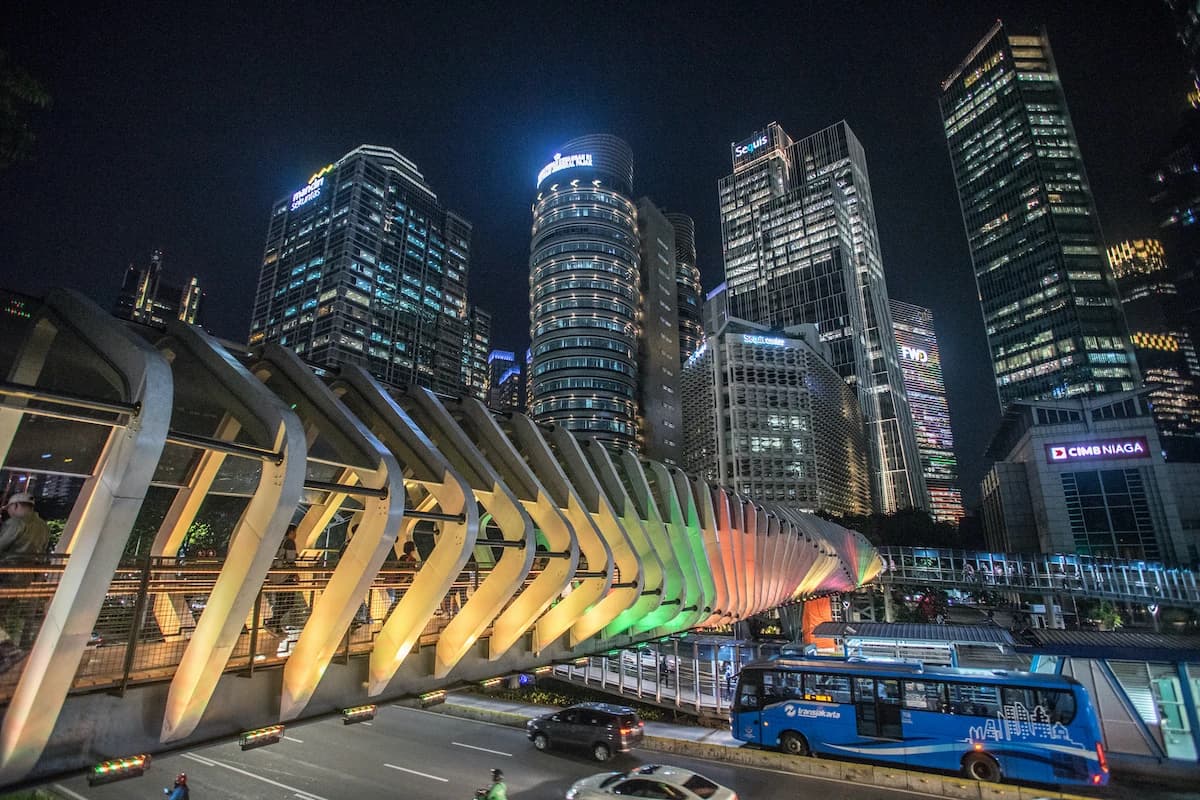 Skyscrapers and a pedestrian bridge illuminated at night in Jakarta's SCBD.