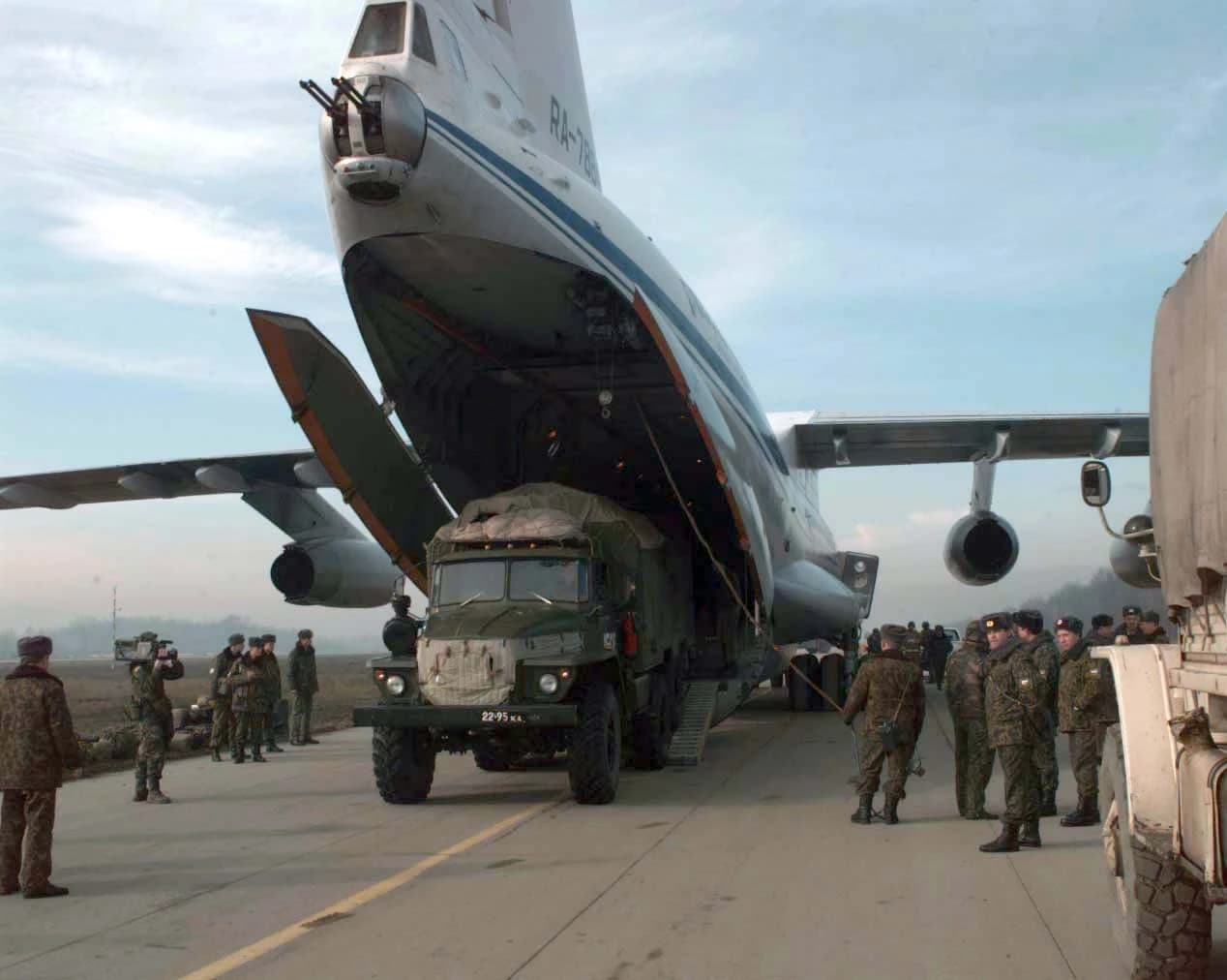 Military personnel loading a large truck into a Russian IL-76T cargo plane.