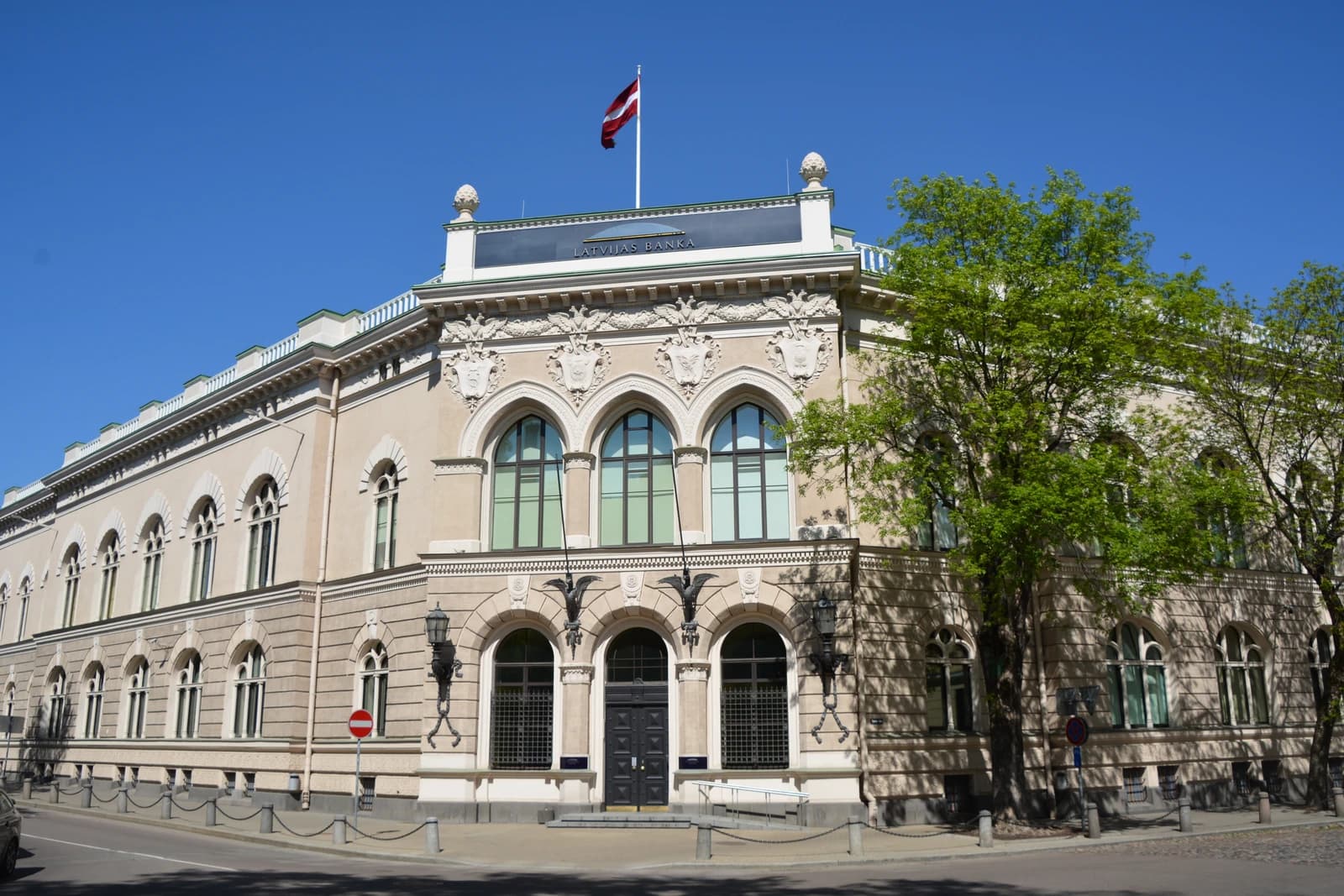 Exterior of the Bank of Latvia building in Riga, Latvia, with a flag on the roof.