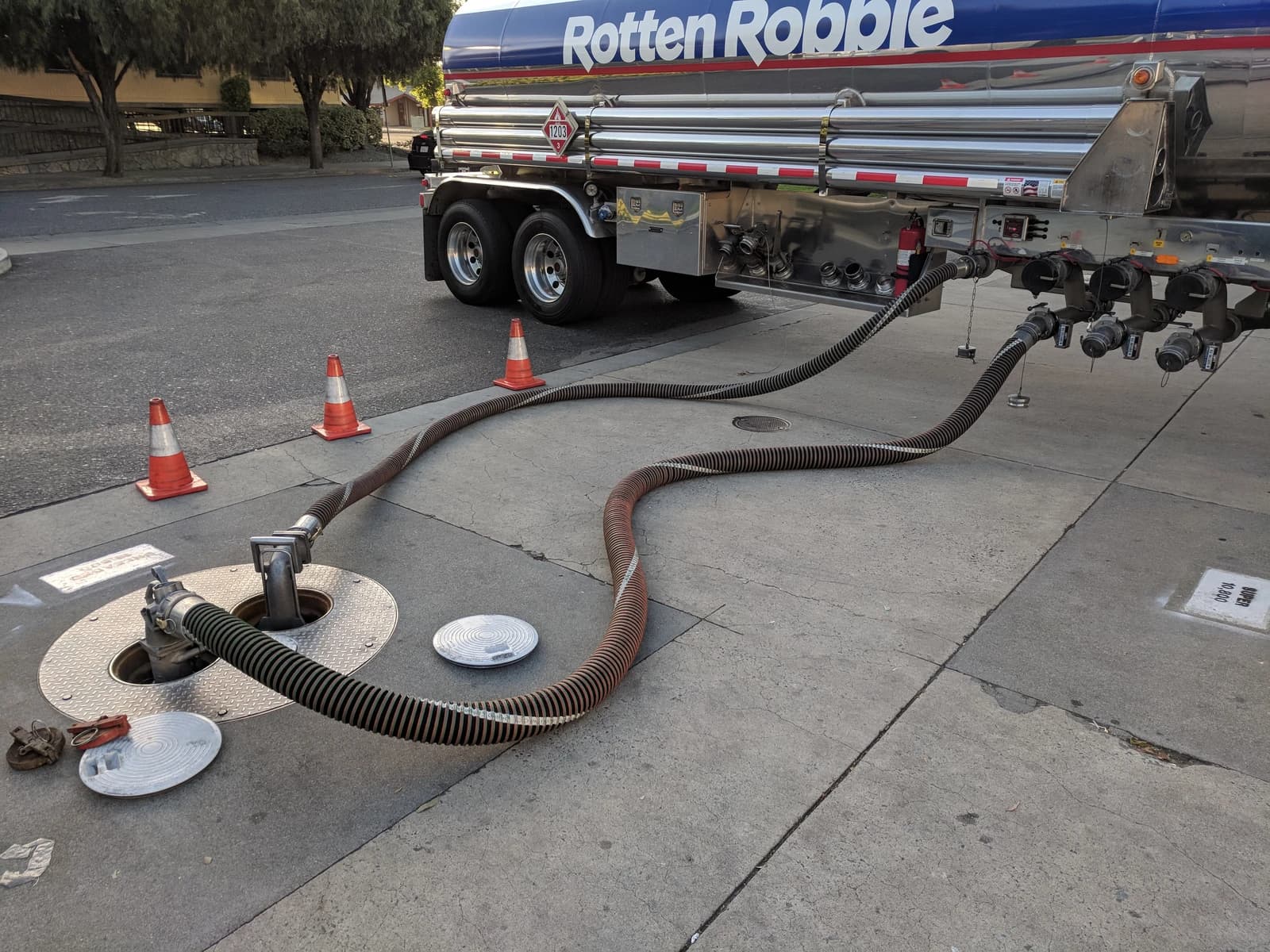 Hoses from a fuel tanker refilling underground tanks at a gas station.