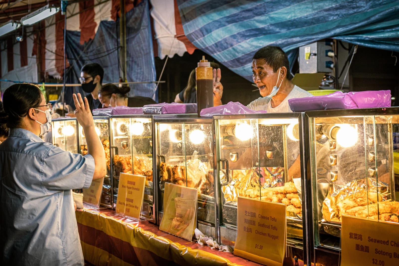Vendor at a Malaysian night market interacting with a customer.