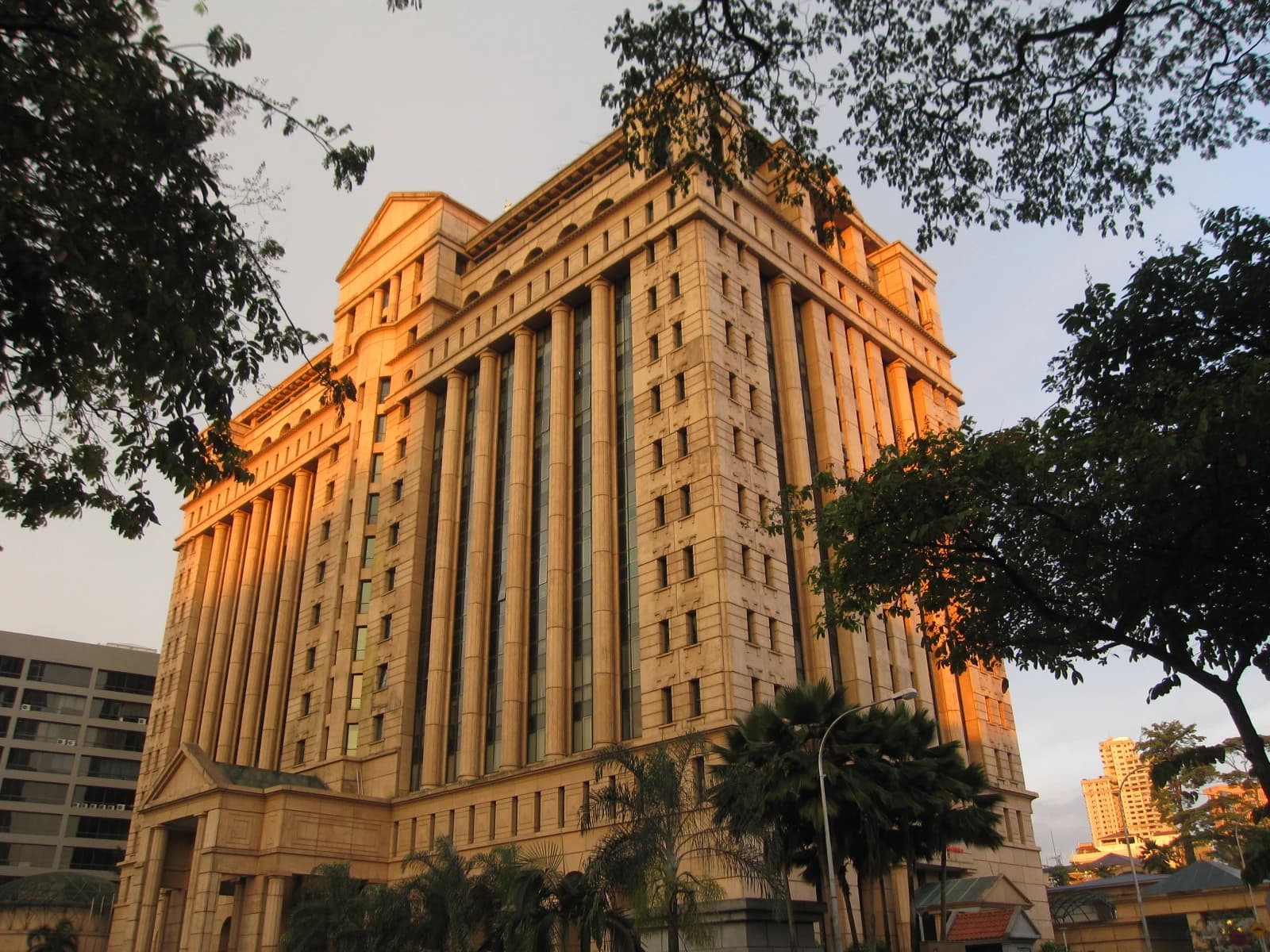 Bursa Malaysia building, a tall structure with columns, stands against a bright sky.