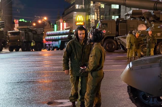 Russian soldiers standing near military vehicles with large missiles on trailers at night.