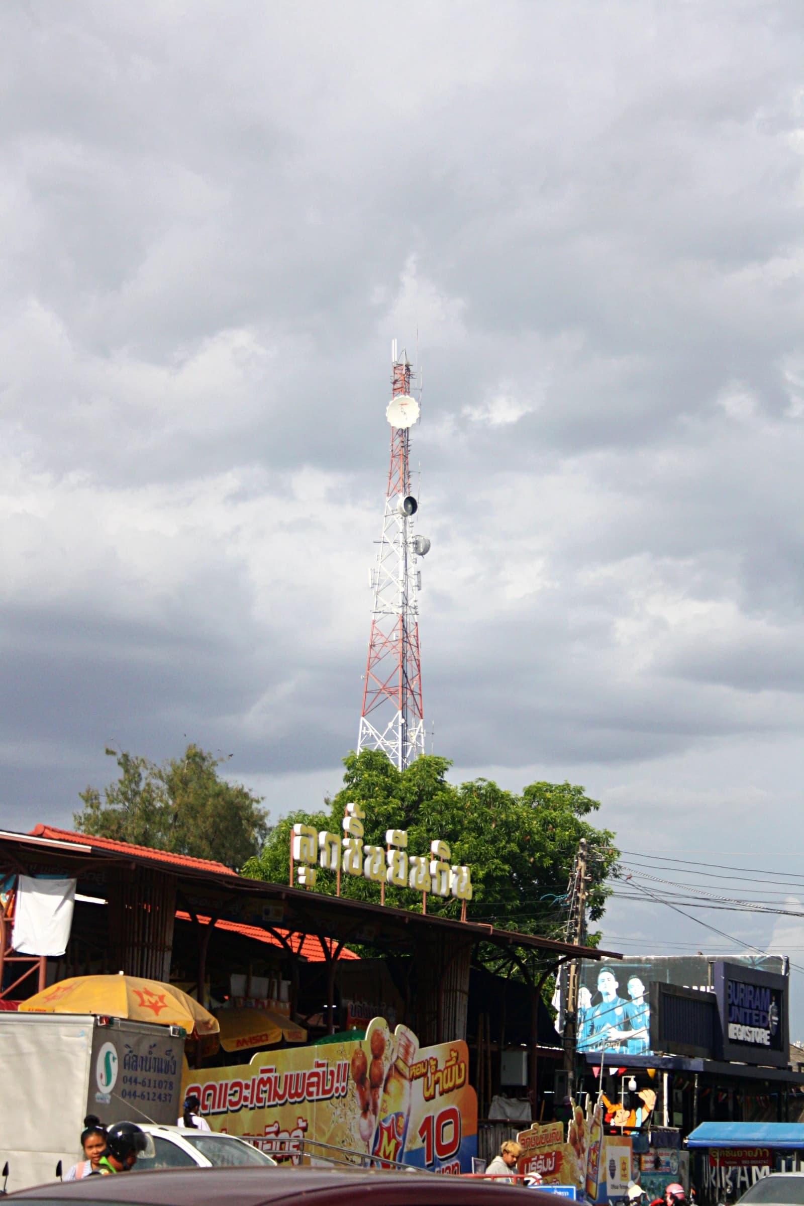 Telecommunication tower with dishes and antennae extending towards a cloudy sky.