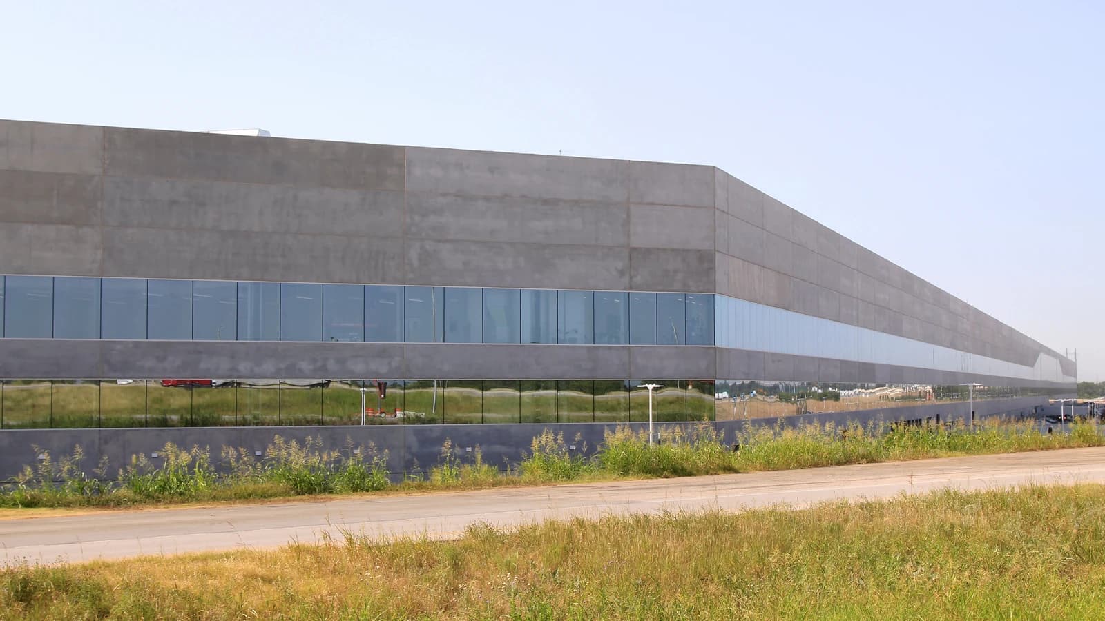 Exterior view of Tesla's Gigafactory Texas, a large industrial building with long horizontal windows.