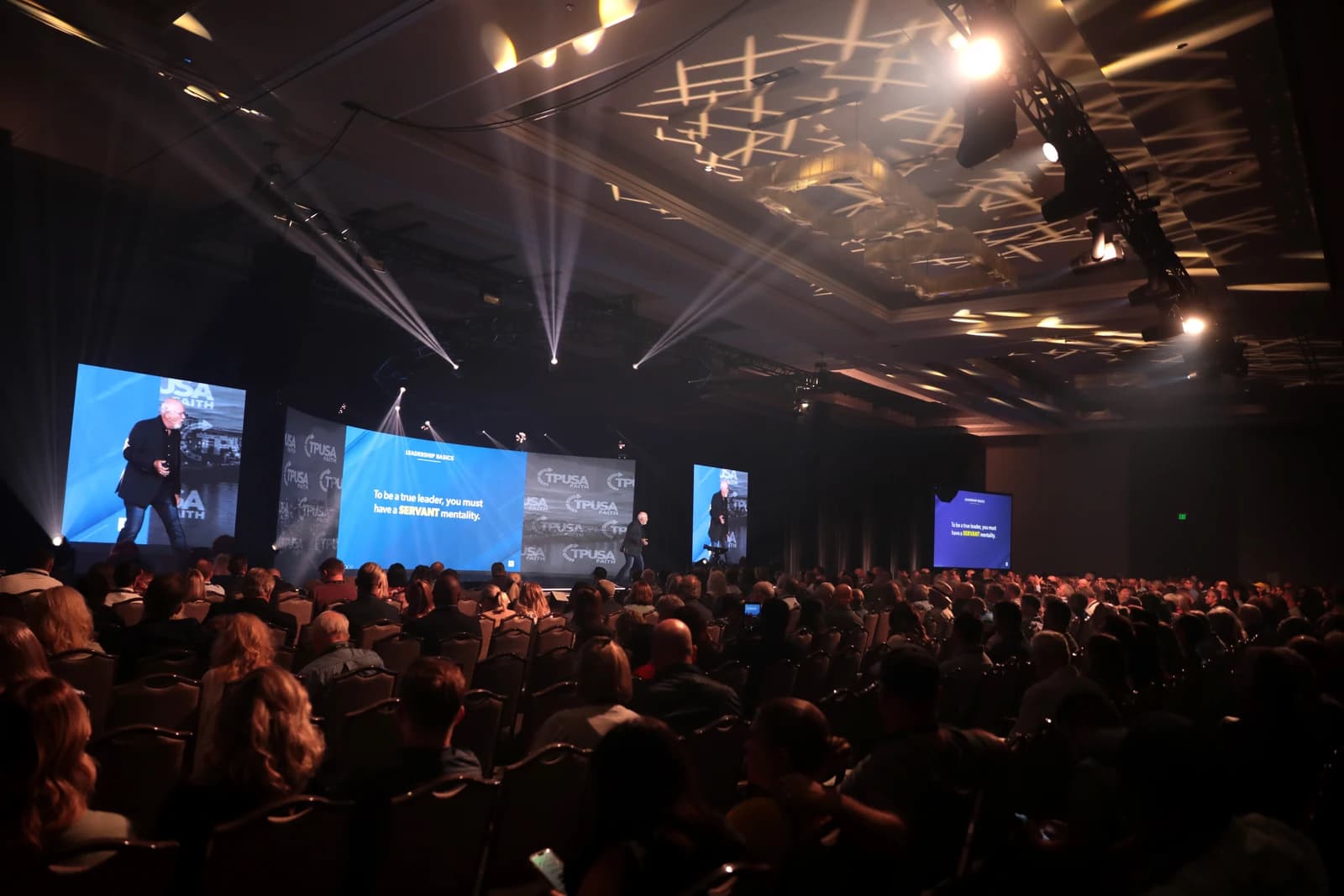 Dave Ramsey speaks on stage to an audience at a large conference.