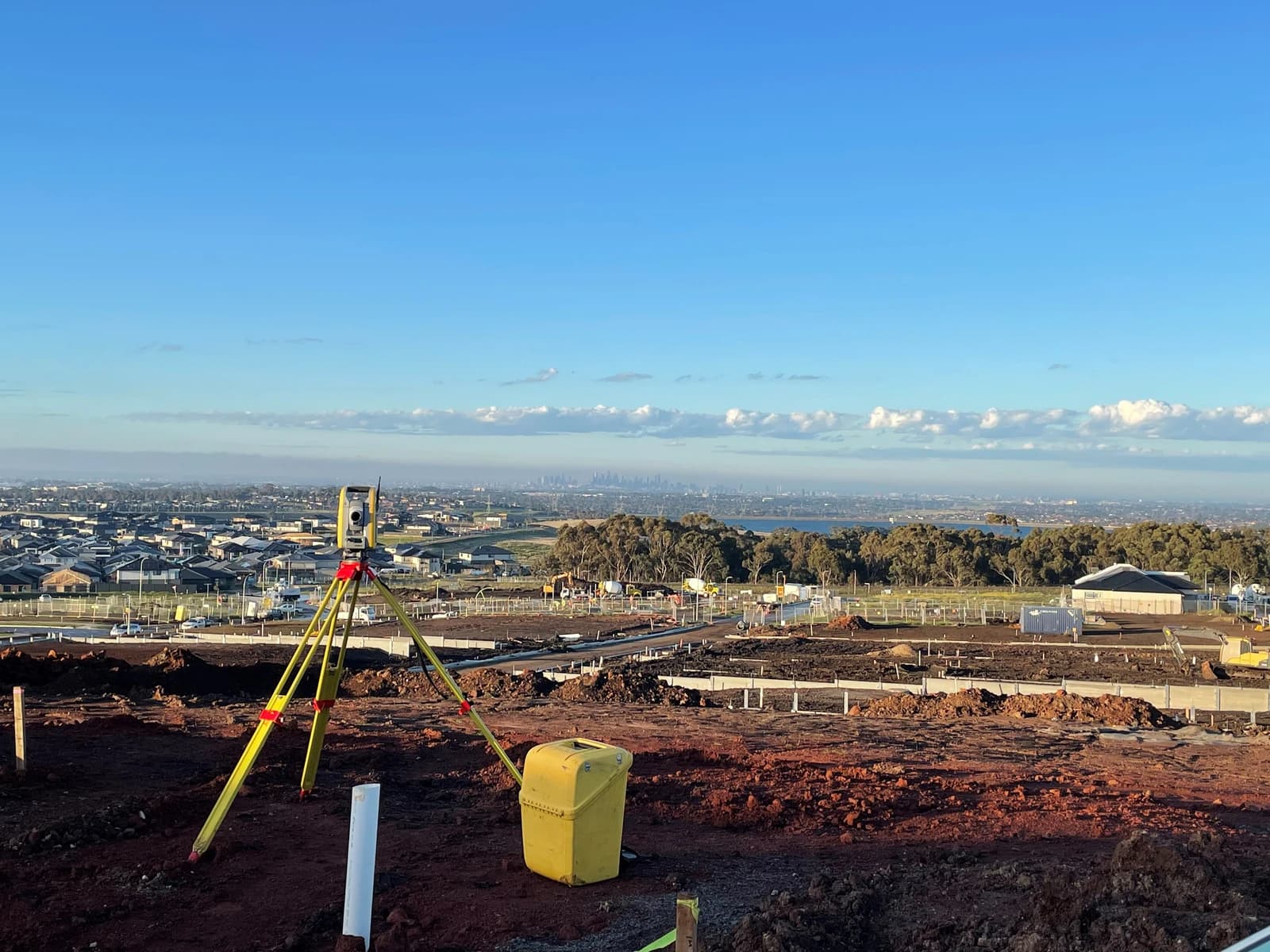 Total station surveying equipment set up at a construction site overlooking a new housing development.