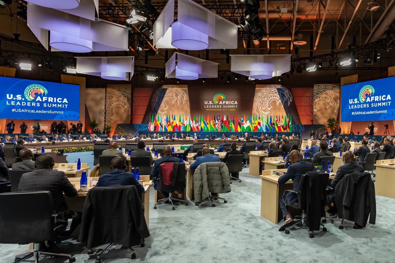 Attendees seated at tables during the U.S.-Africa Leaders Summit, with flags in the background.