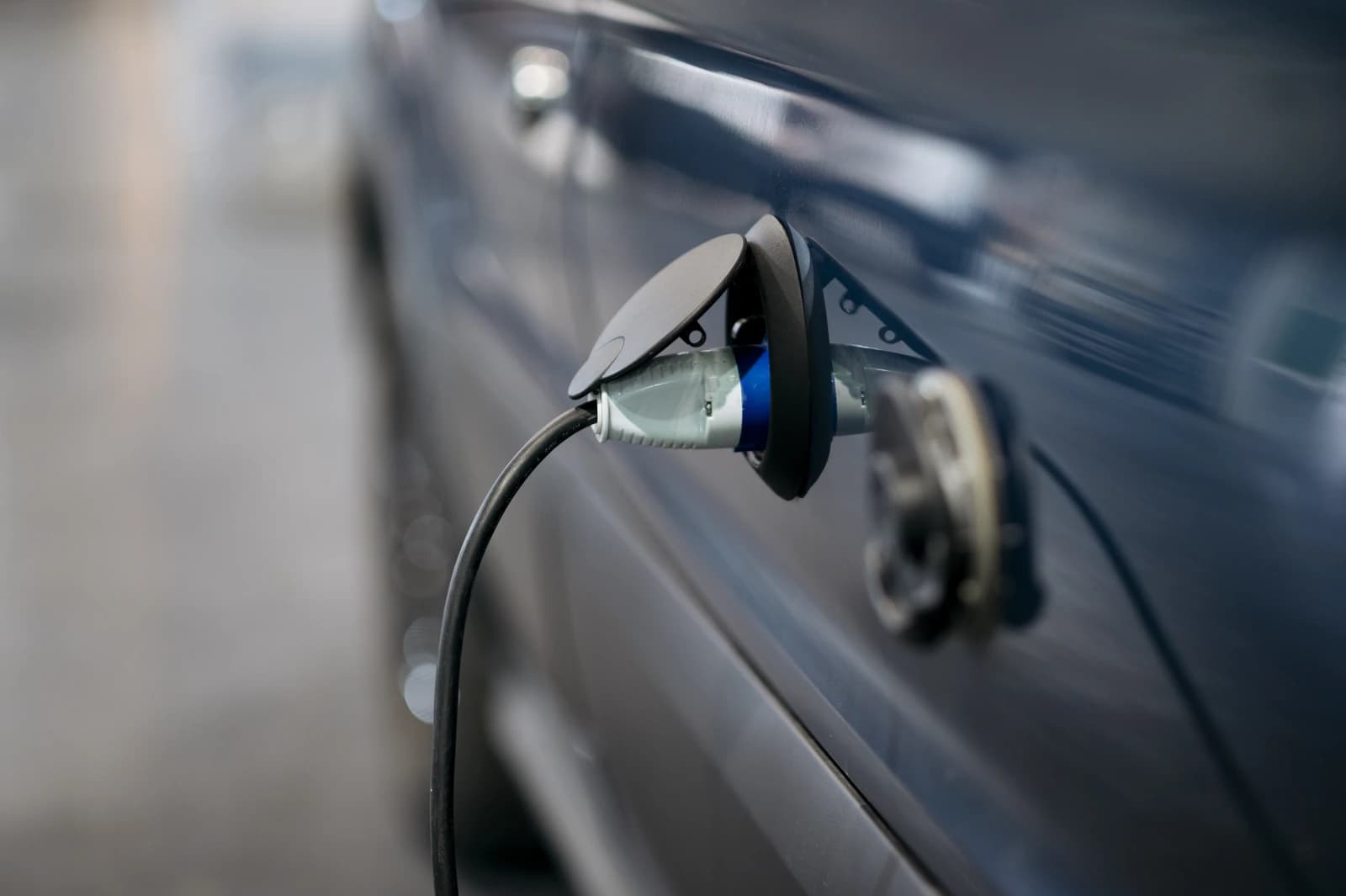 An electric car charges at a station with the charging cable connected to the vehicle.