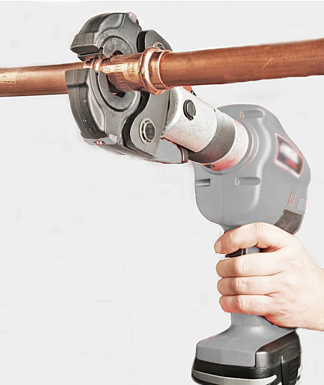 A person holds a battery-powered crimping tool on a copper pipe.