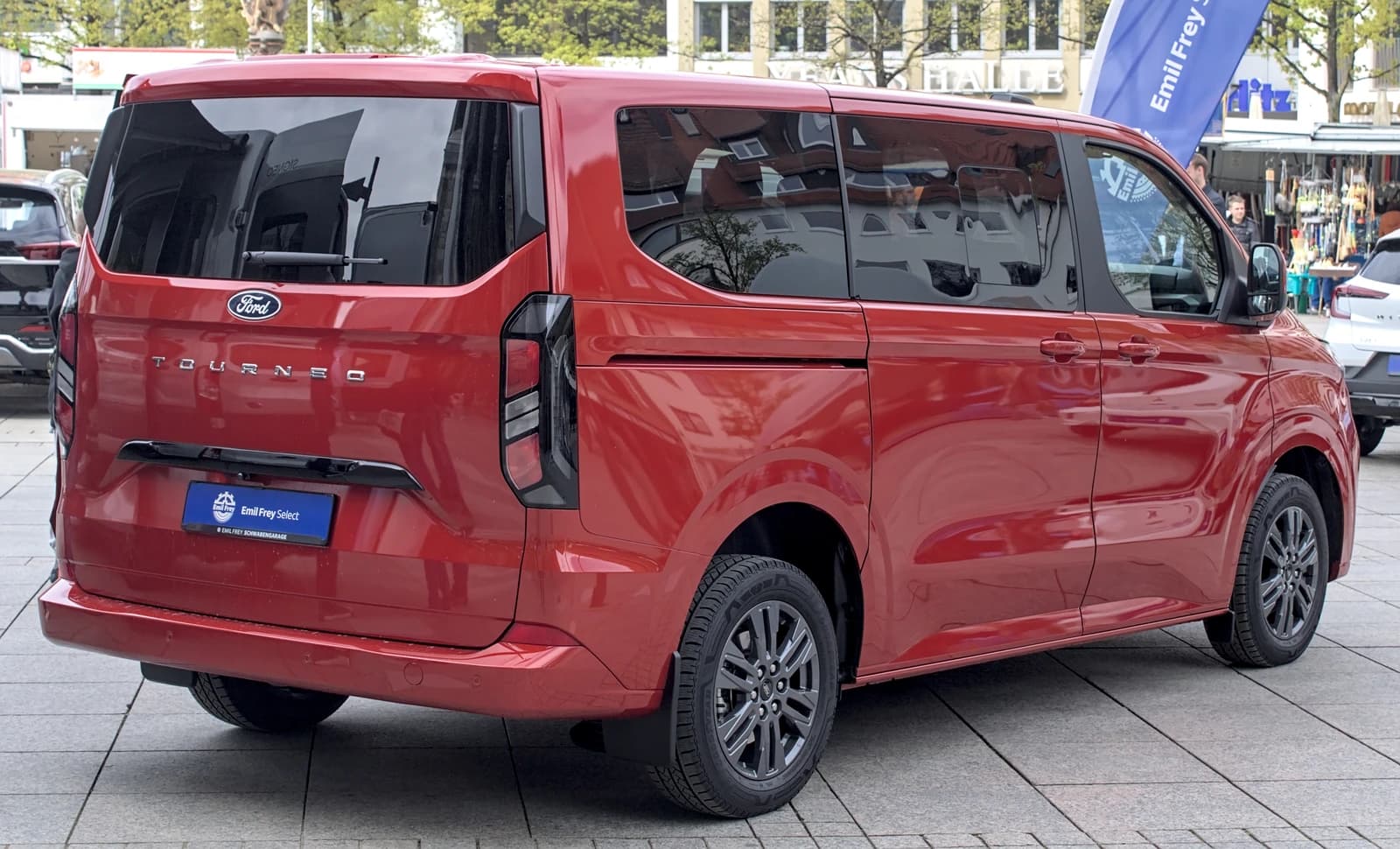 Rear view of a red Ford Tourneo Custom van parked on pavement.