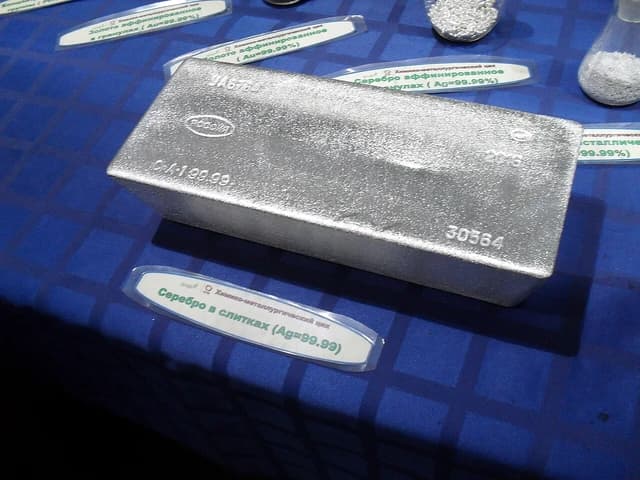 An Uralelectromed silver bar with 99.99% purity displayed on a blue surface.