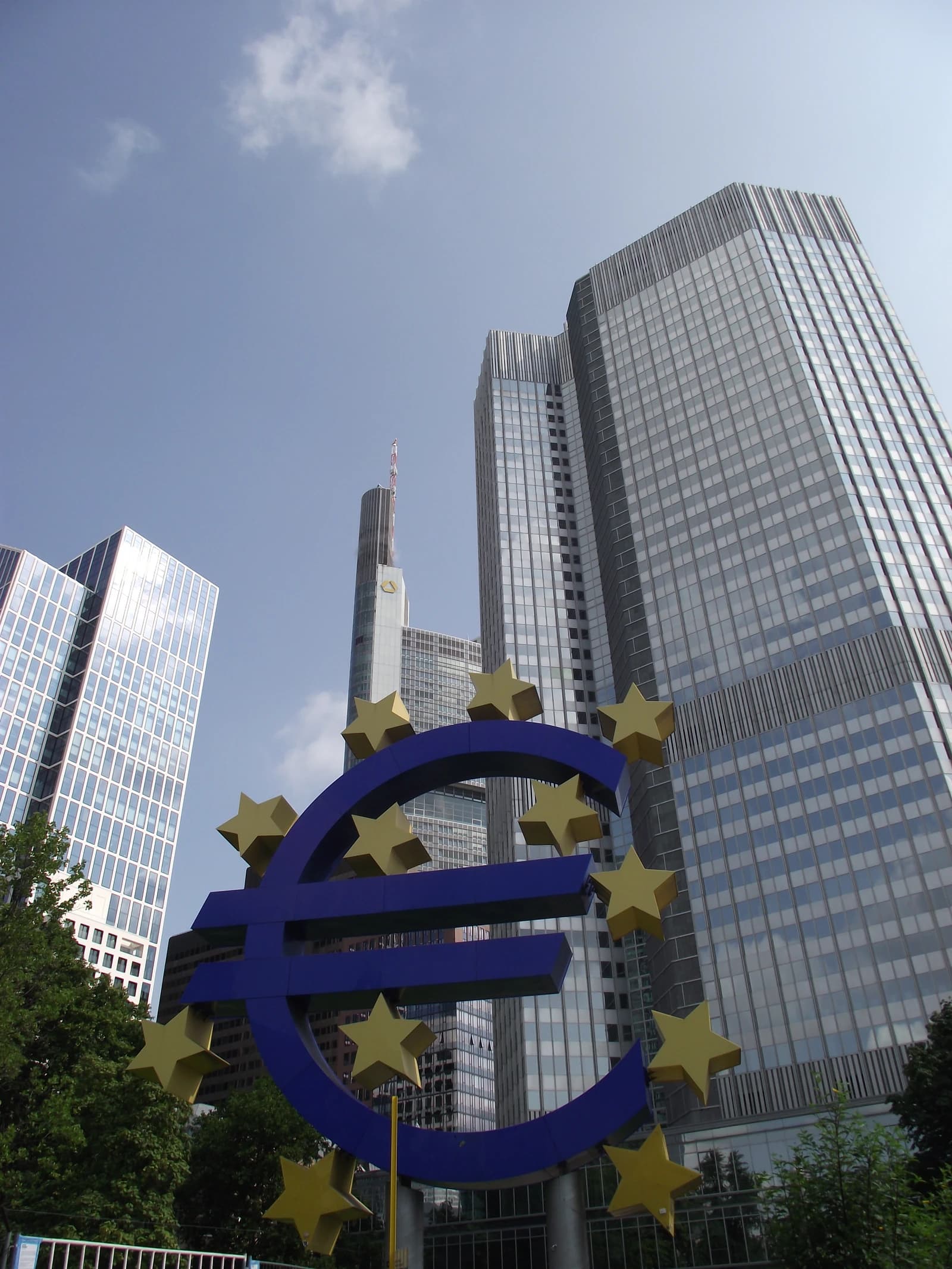 Euro symbol sculpture with skyscrapers of Frankfurt am Main in the background.