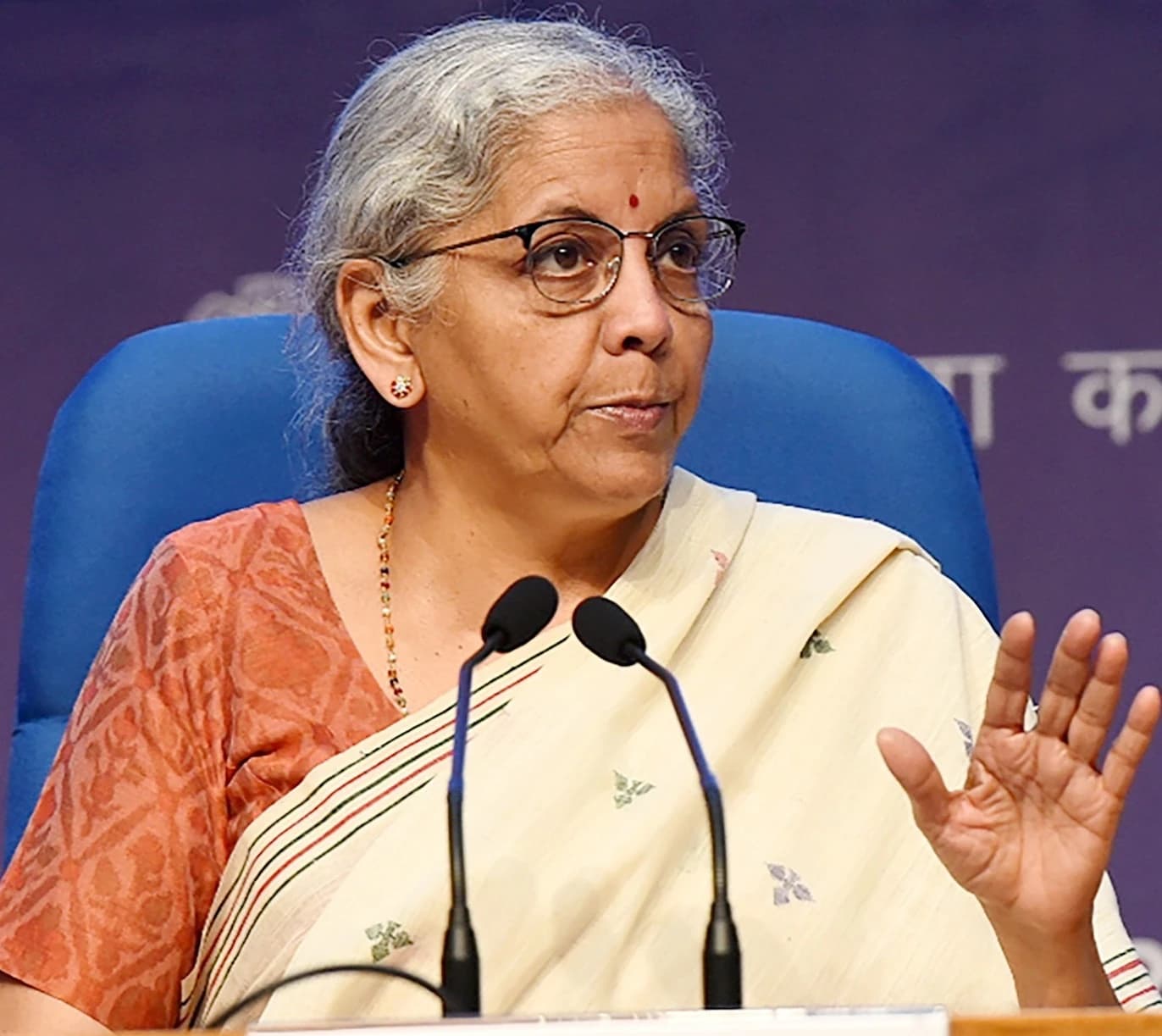 Union Minister of Finance Nirmala Sitharaman addressing a press conference at a podium.