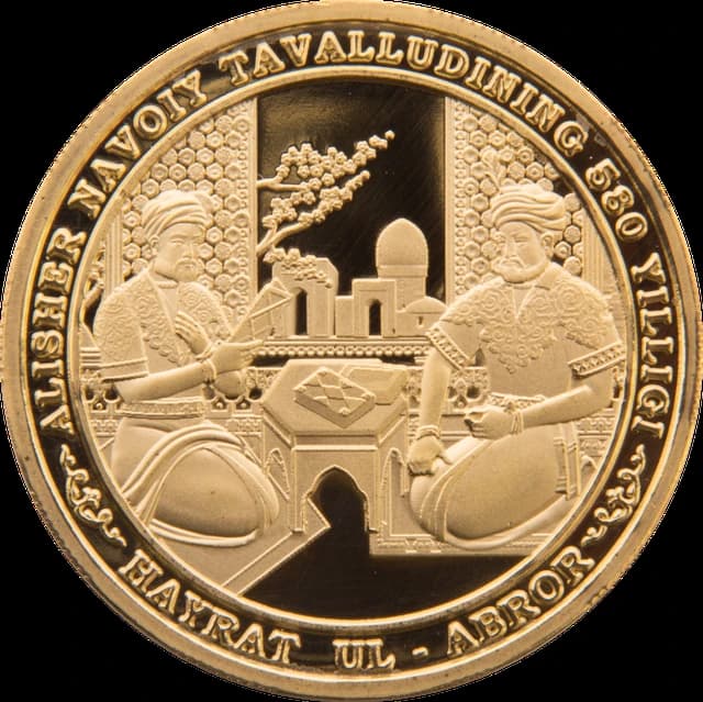 Close-up of a gold coin showing two figures in traditional attire, with text around the rim.