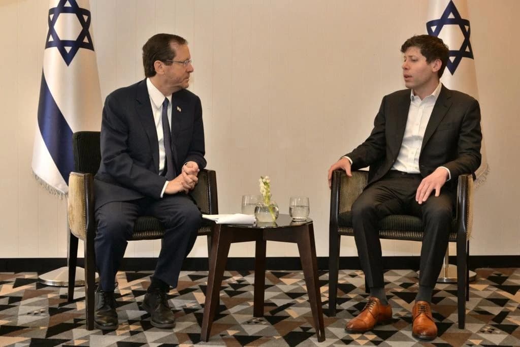 Isaac Herzog and Sam Altman sit facing each other during a meeting.