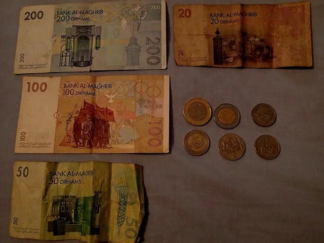 Moroccan dirham banknotes in various denominations and several coins laid out on a dark surface.