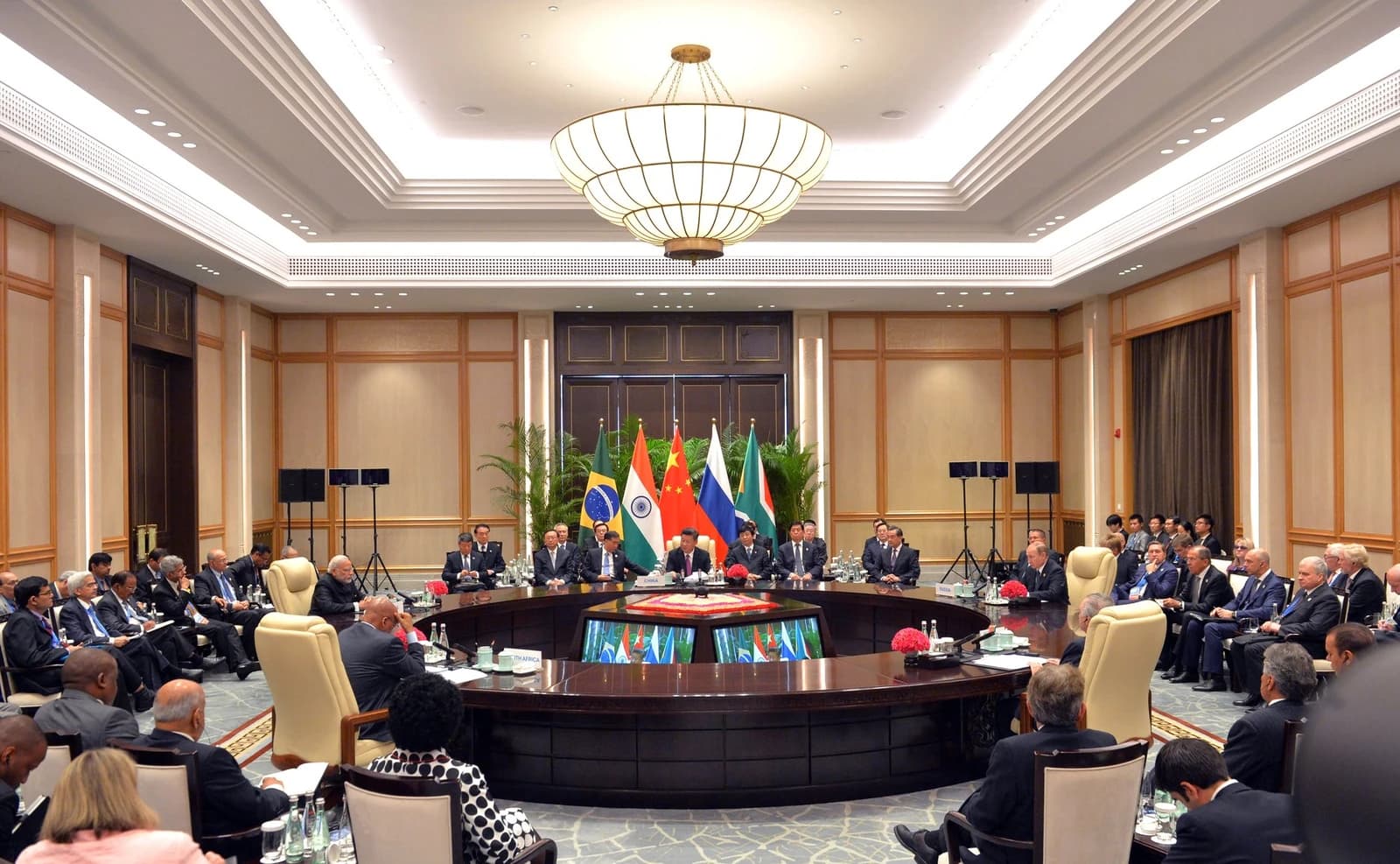 BRICS leaders including Xi Jinping and Vladimir Putin seated at a large circular table.