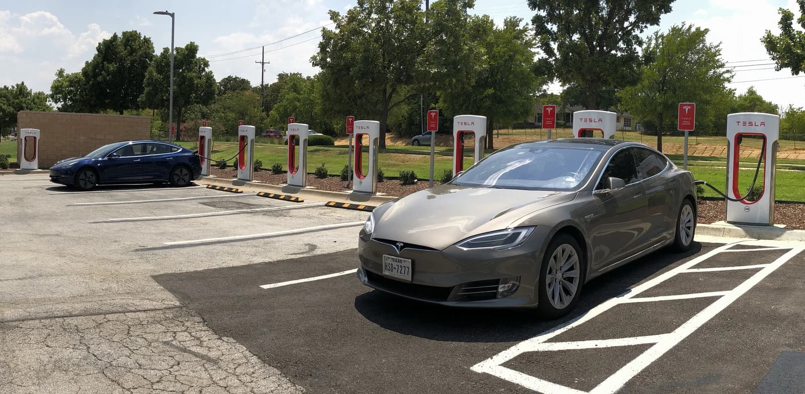 Two Tesla electric vehicles parked at a Tesla Supercharger station in Southlake, Texas.