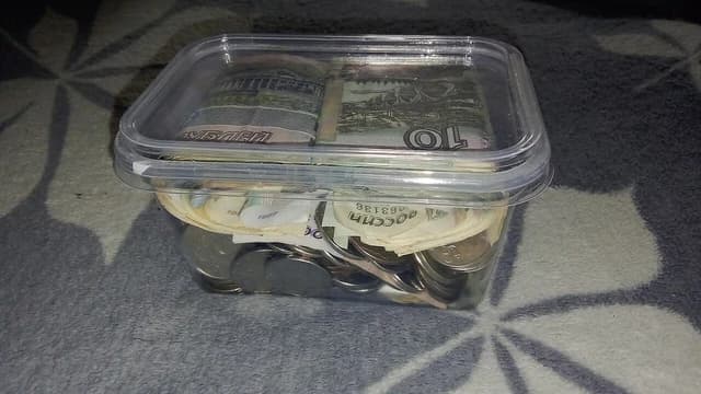 Plastic container holding various Russian ruble banknotes and coins.